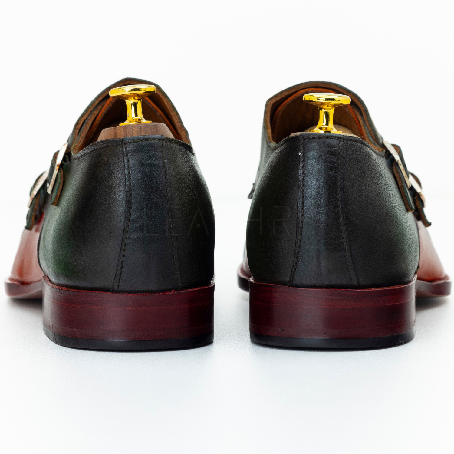Black leather shoes with gold buckles on a white background