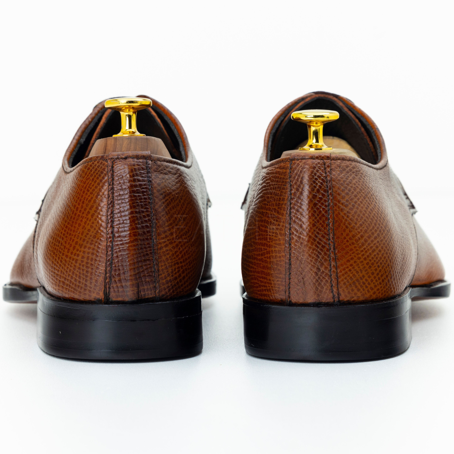 Brown leather shoes with gold accents on a white background