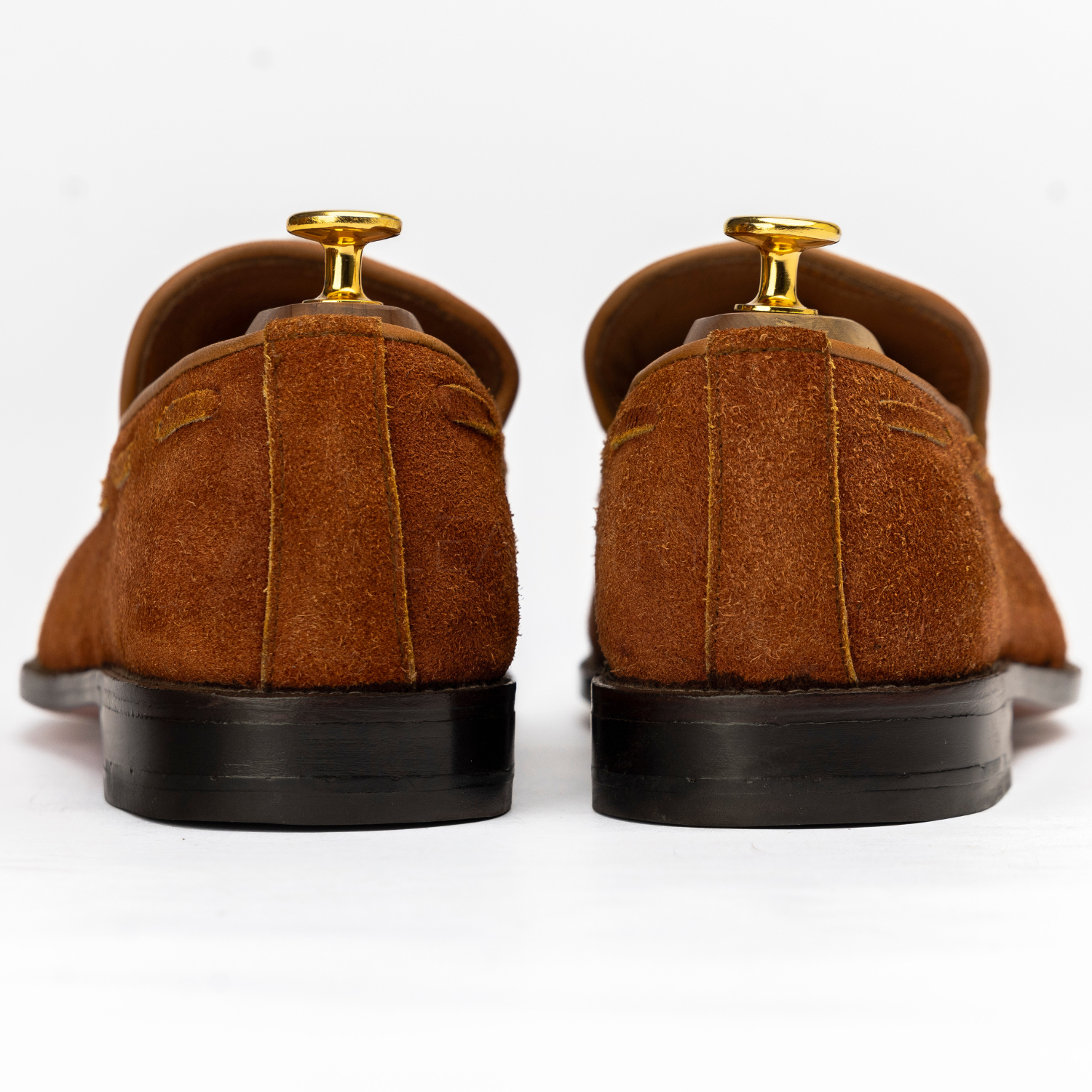 Brown suede shoes on mannequin stands against a white background
