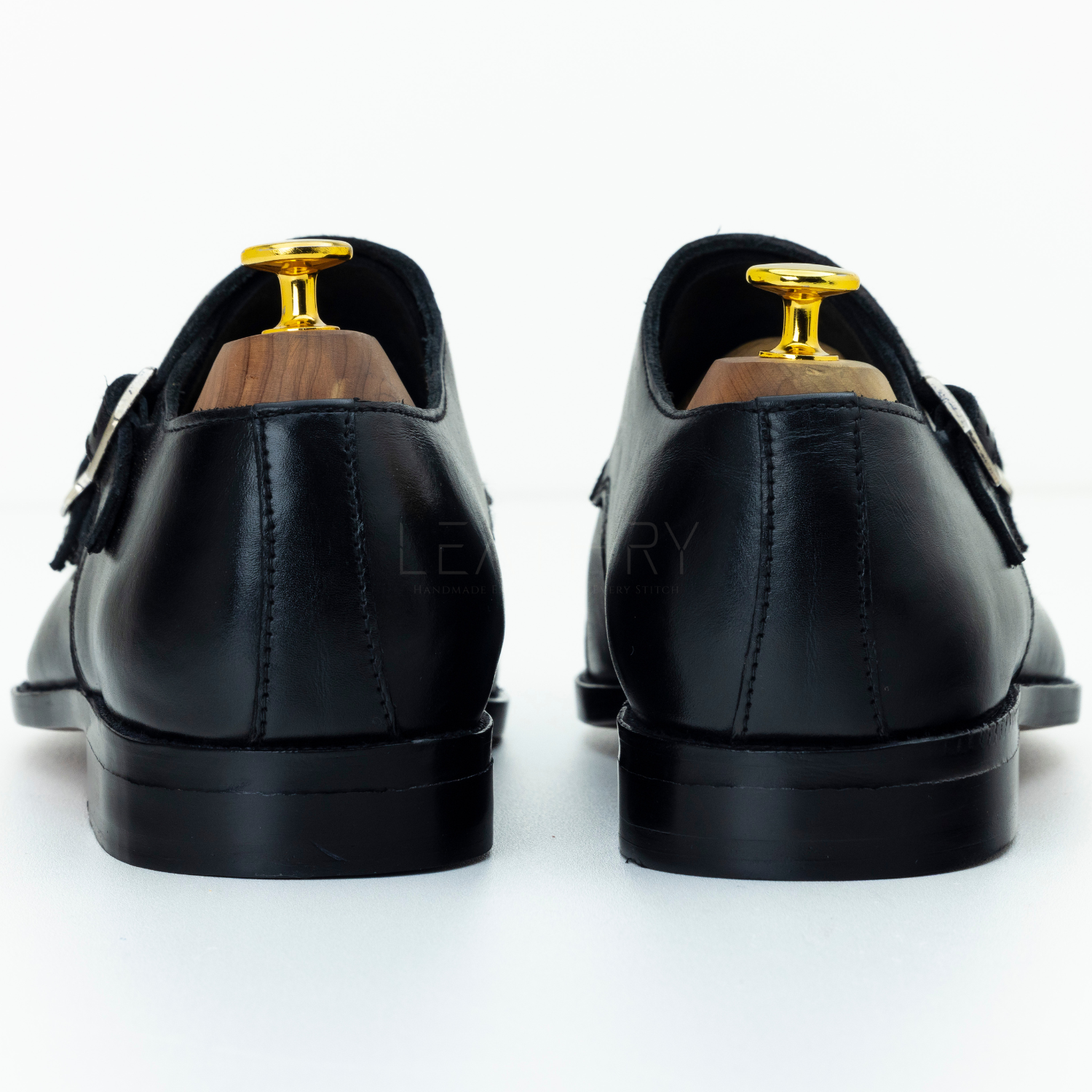 Black leather shoes with gold buckles on a white background