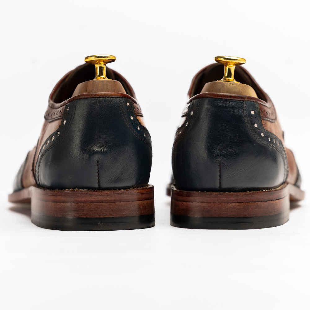 Pair of black leather dress shoes with brown soles on a white background