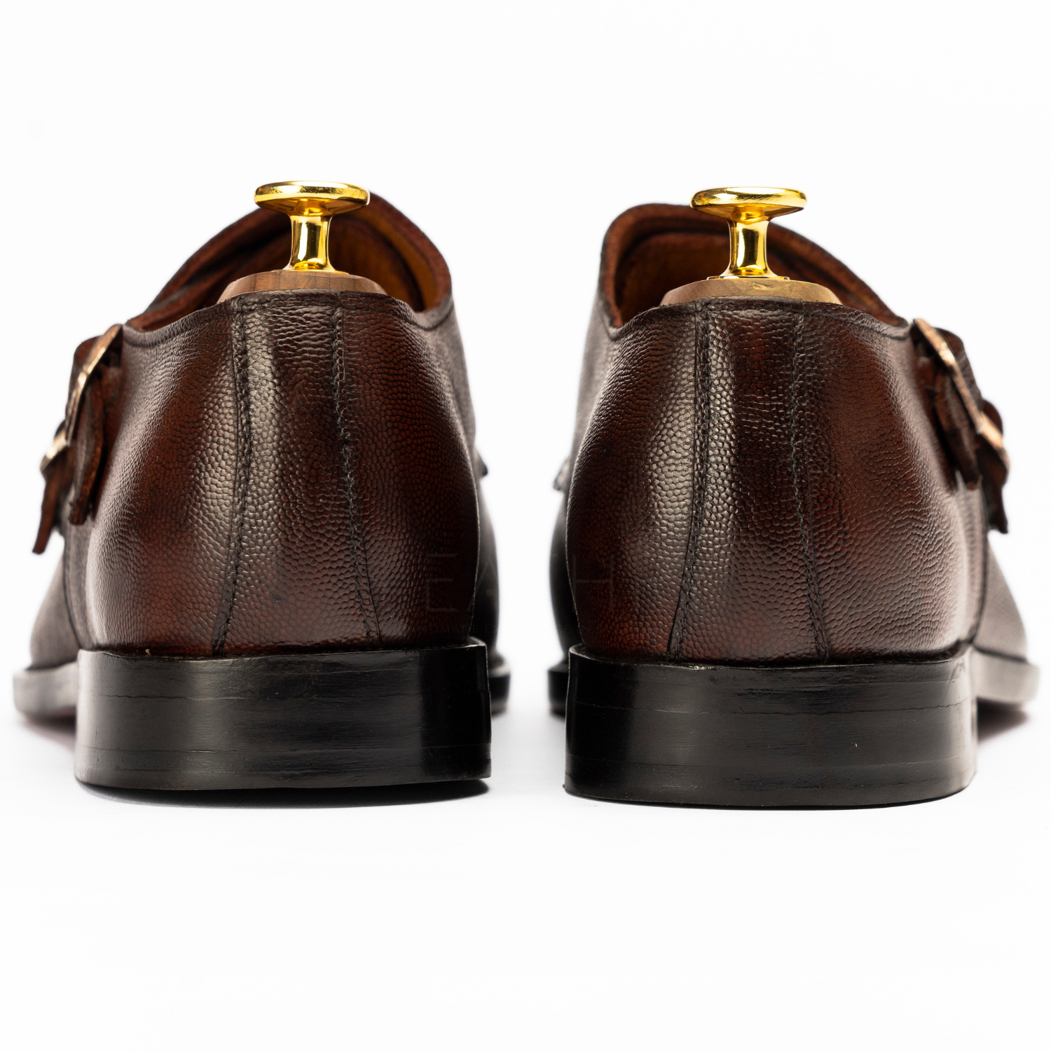 Brown leather shoes with gold buckles on a white background