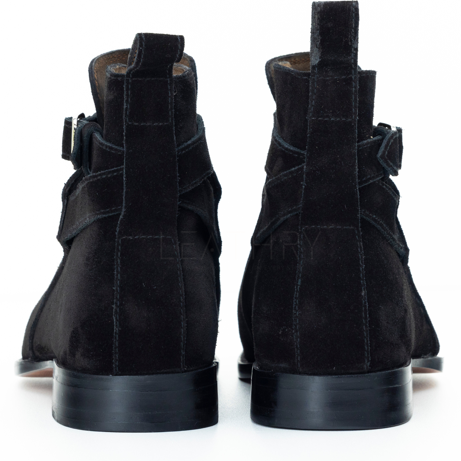 Black suede high-top boots with strap details on a white background