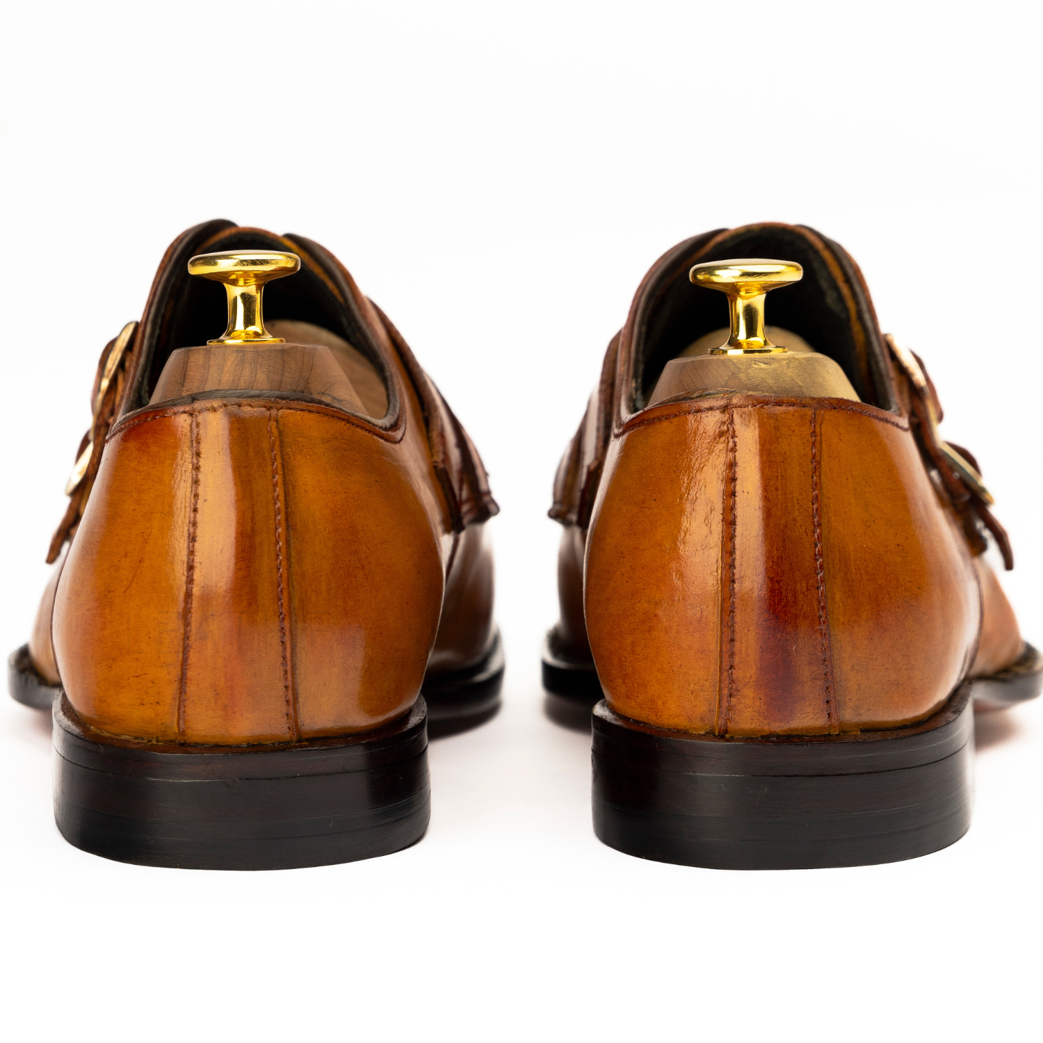 Brown leather shoes with gold buckles on a white background