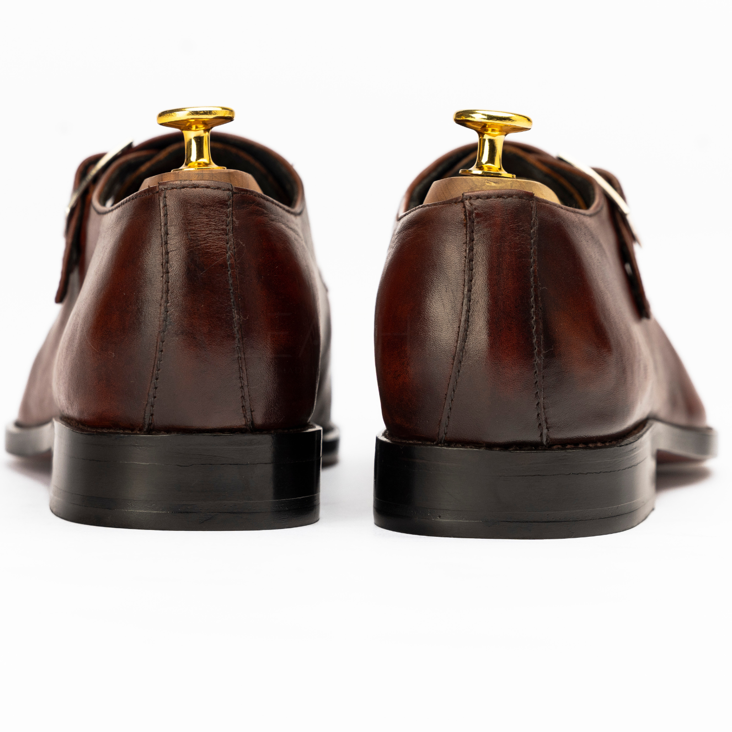Brown leather dress shoes with gold eyelets on a white background