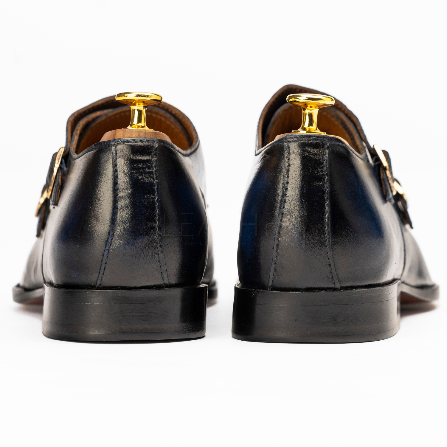 Black leather shoes with gold buckles on a white background