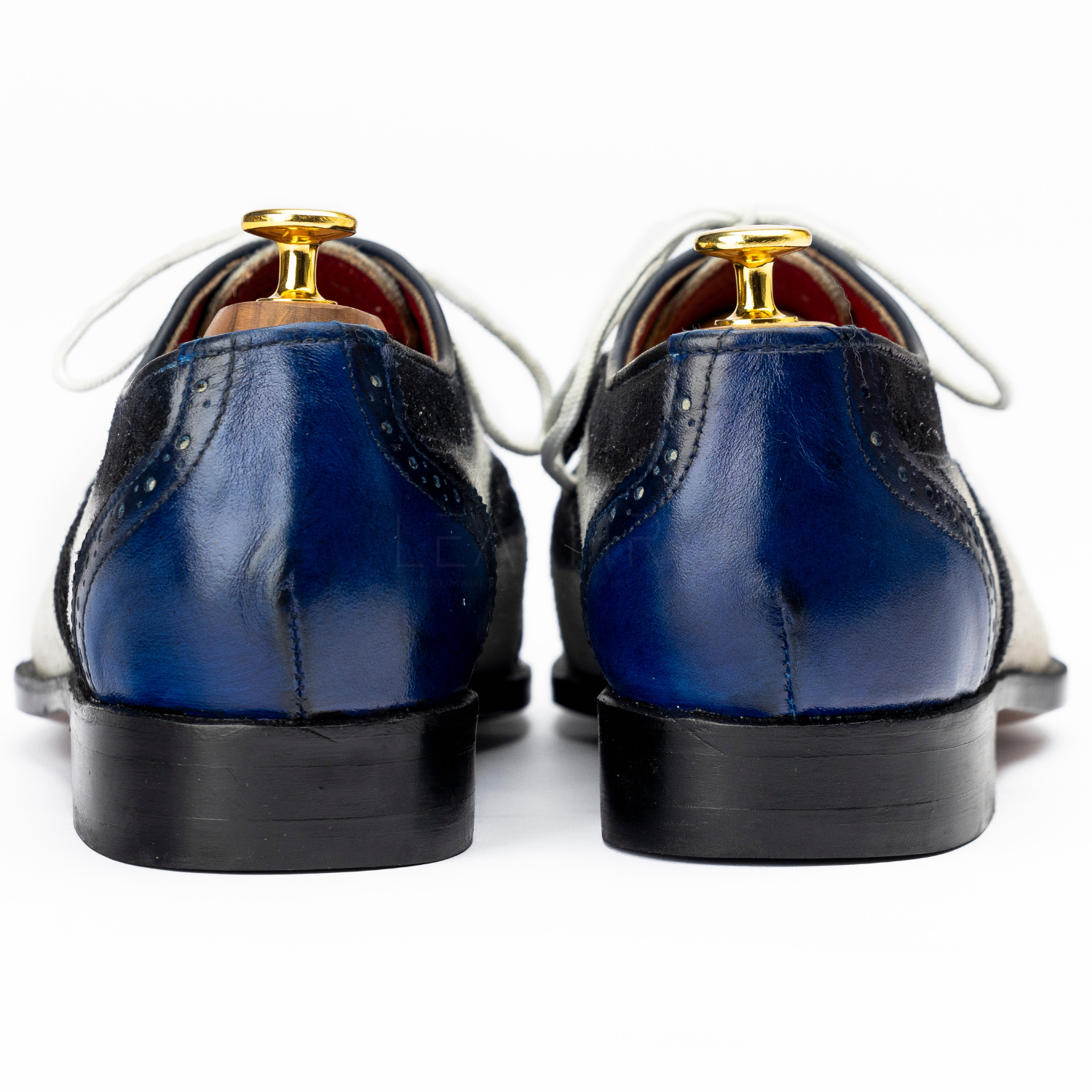 Pair of blue dress shoes with gold buttons on a white background