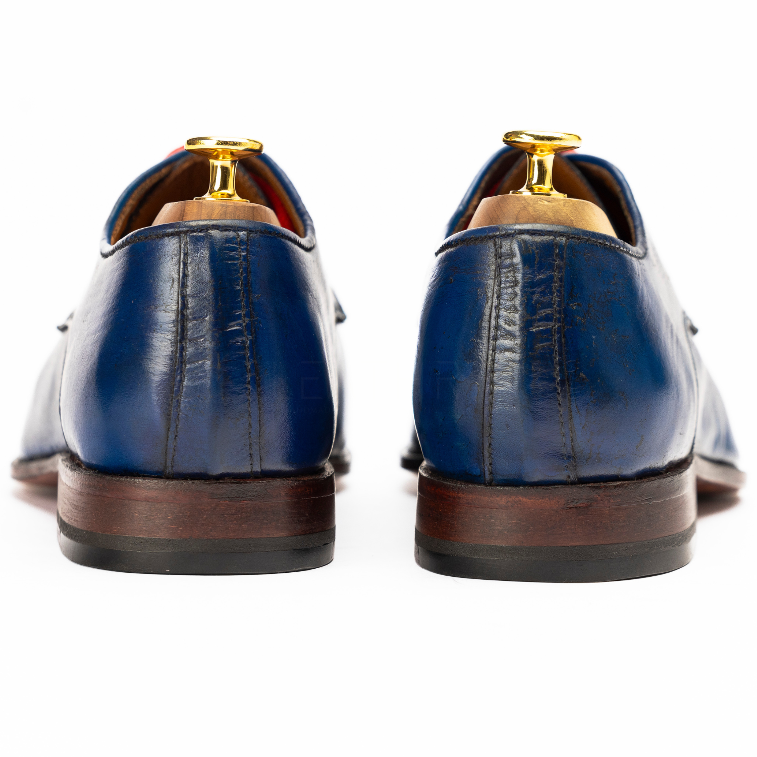 Pair of blue leather shoes with brown soles on a white background