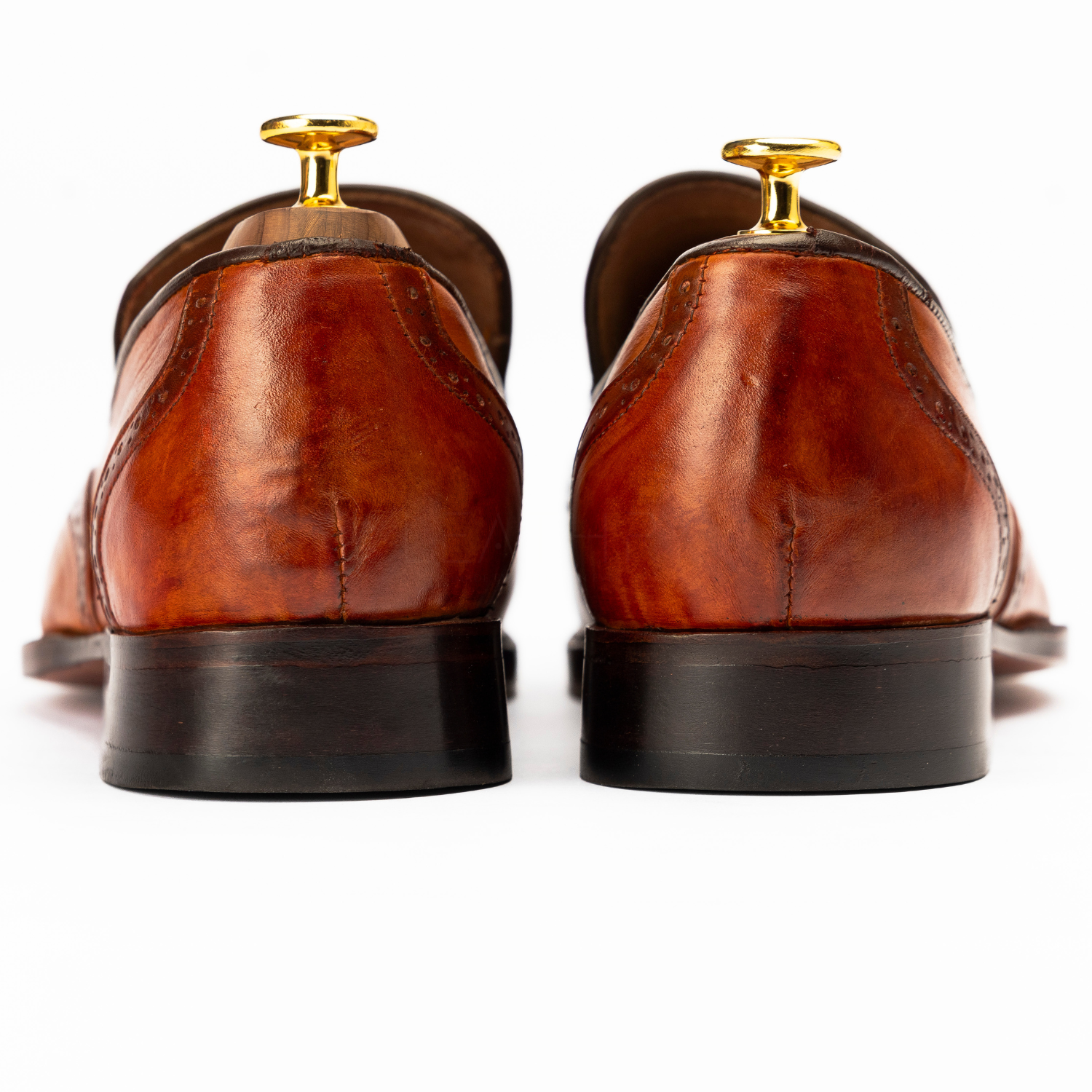 Brown leather shoes with gold accents on a white background