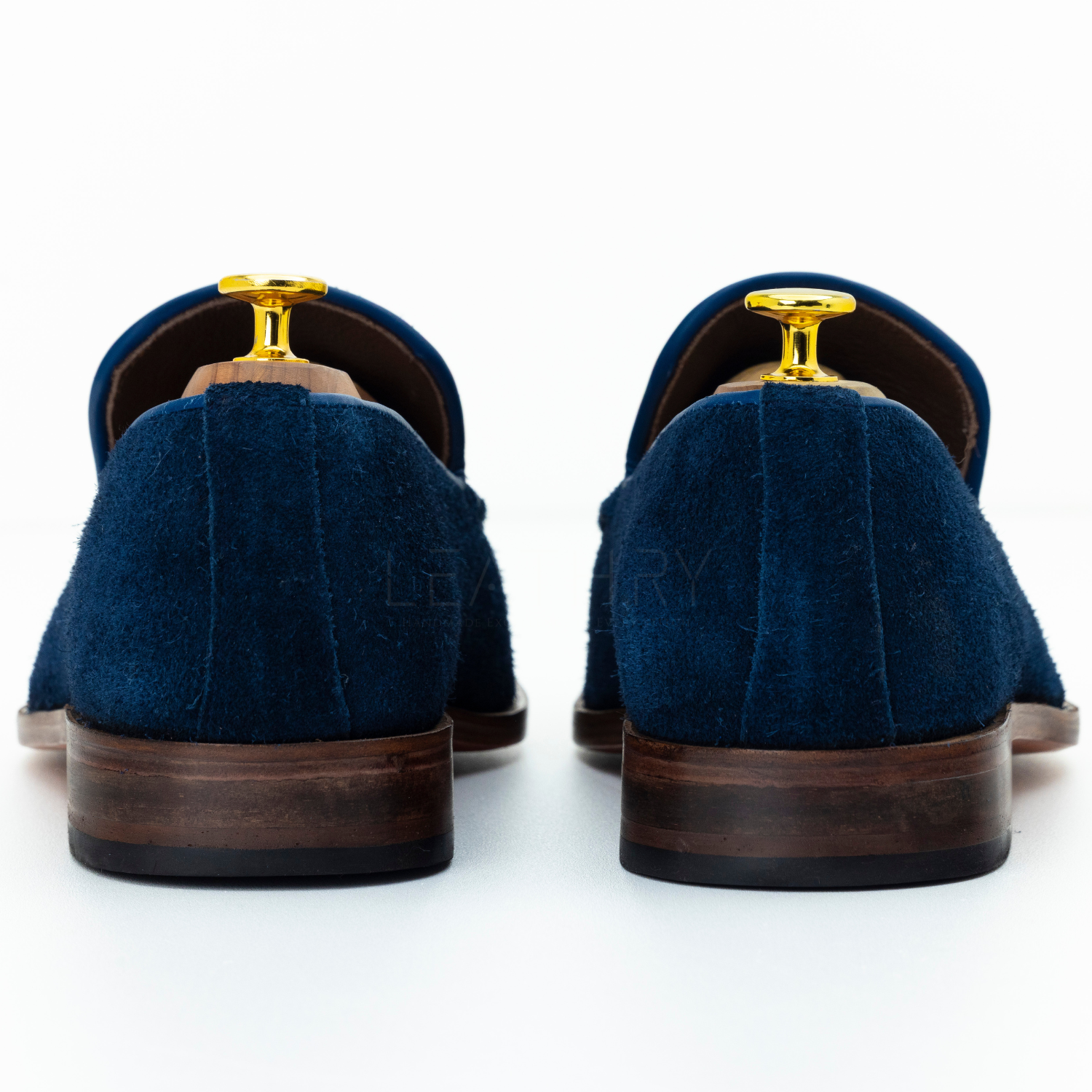 Pair of blue suede shoes with brown soles on a white background