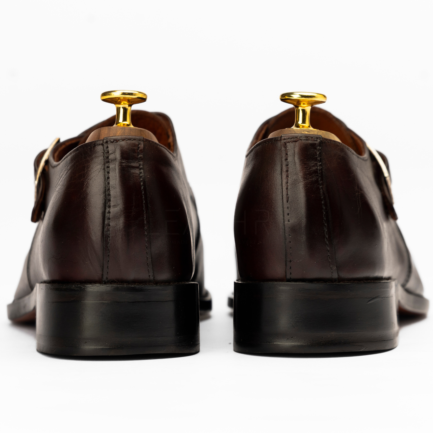 Brown leather shoes with gold buckles on a white background