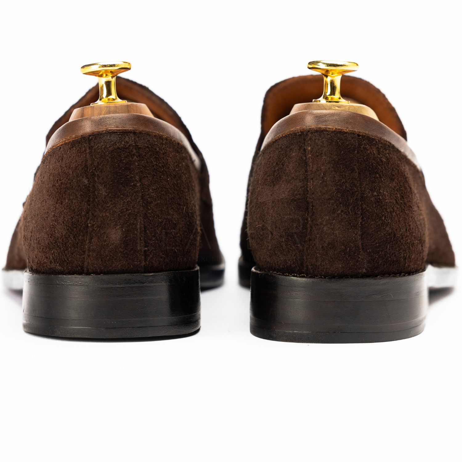 Brown suede loafers with gold accents on a white background
