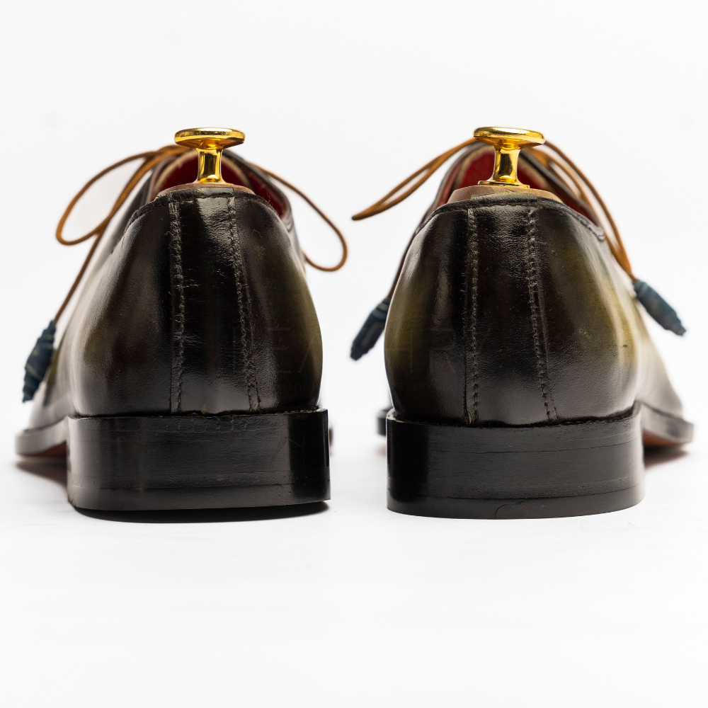 Pair of black dress shoes with gold accents on a white background