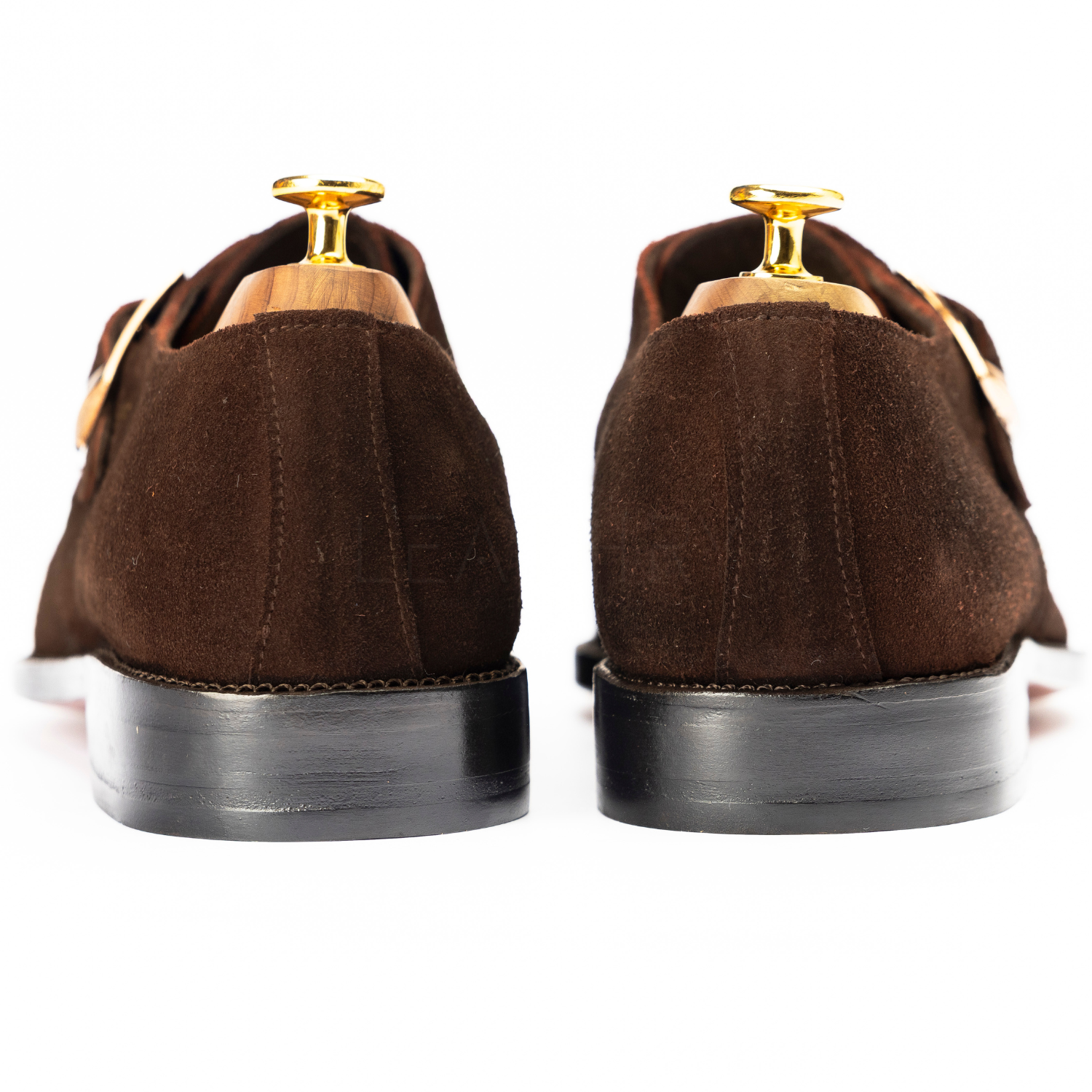 Brown suede shoes with gold buckles on a white background