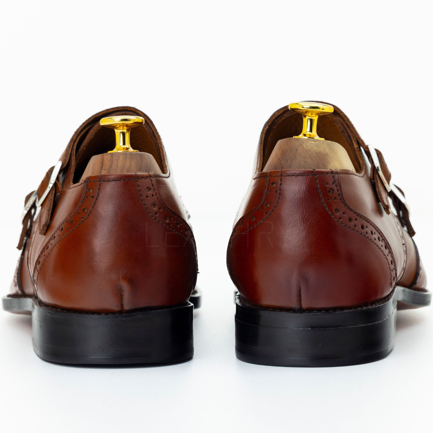 Brown leather shoes with gold accents on a white background