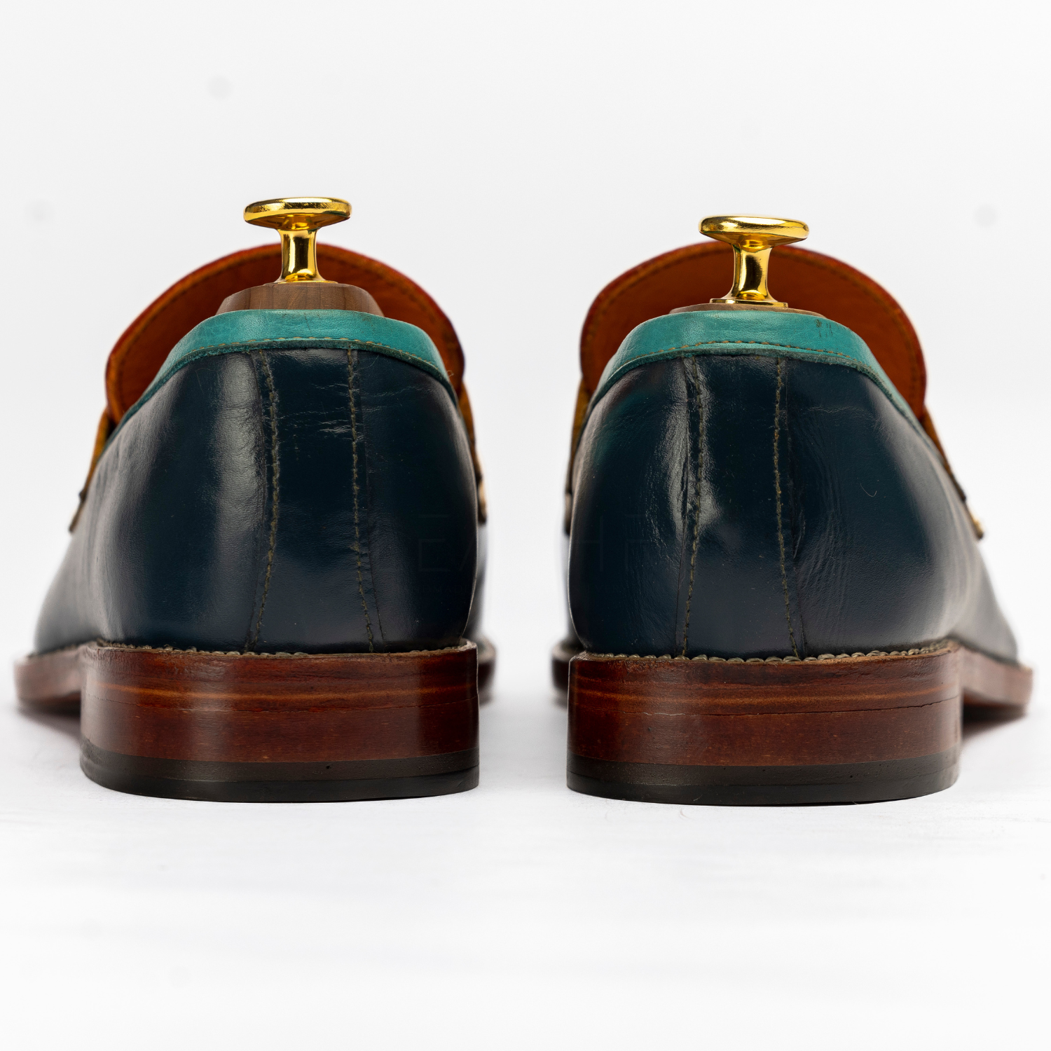 Pair of black leather shoes with brown soles on a white background