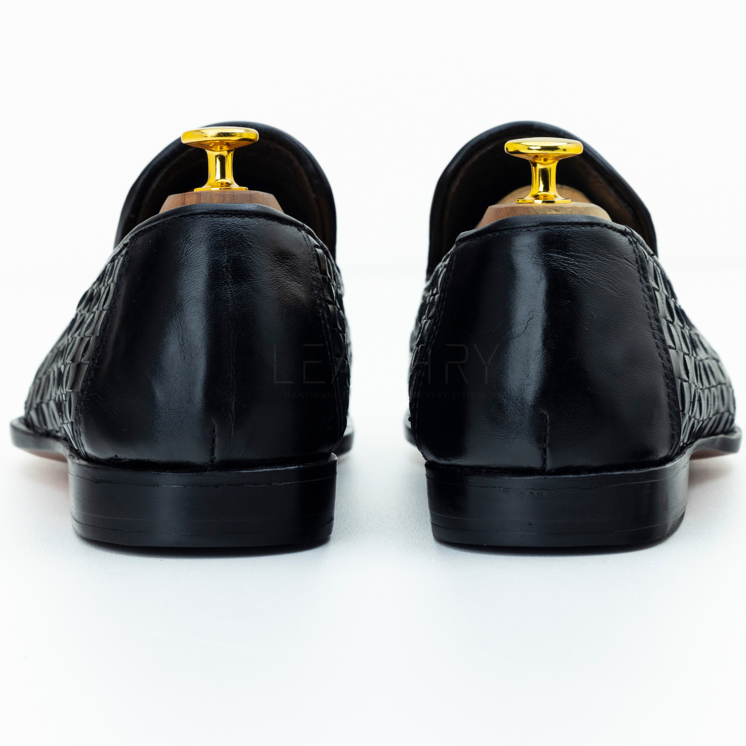 Black leather loafers with gold dress studs on a white background