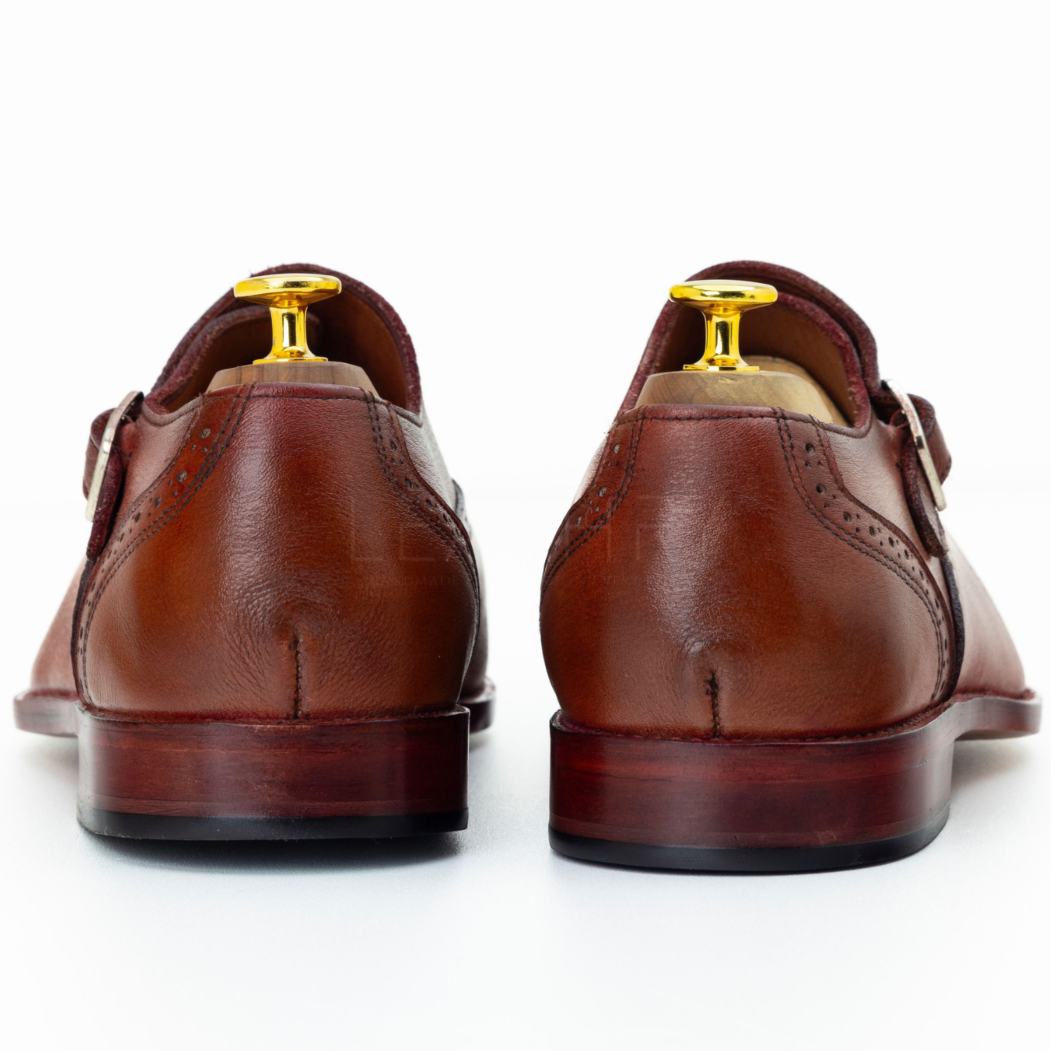 Brown leather shoes with gold buckles on a white background