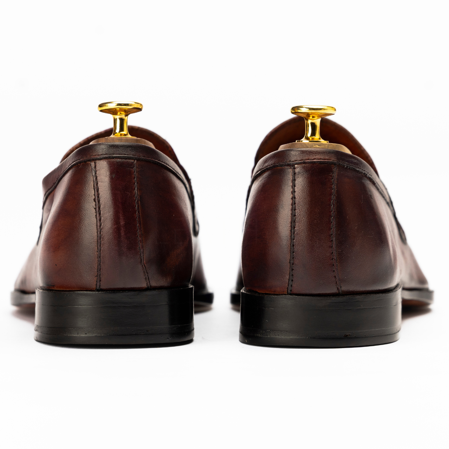 Brown leather shoes with gold dress studs on a white background