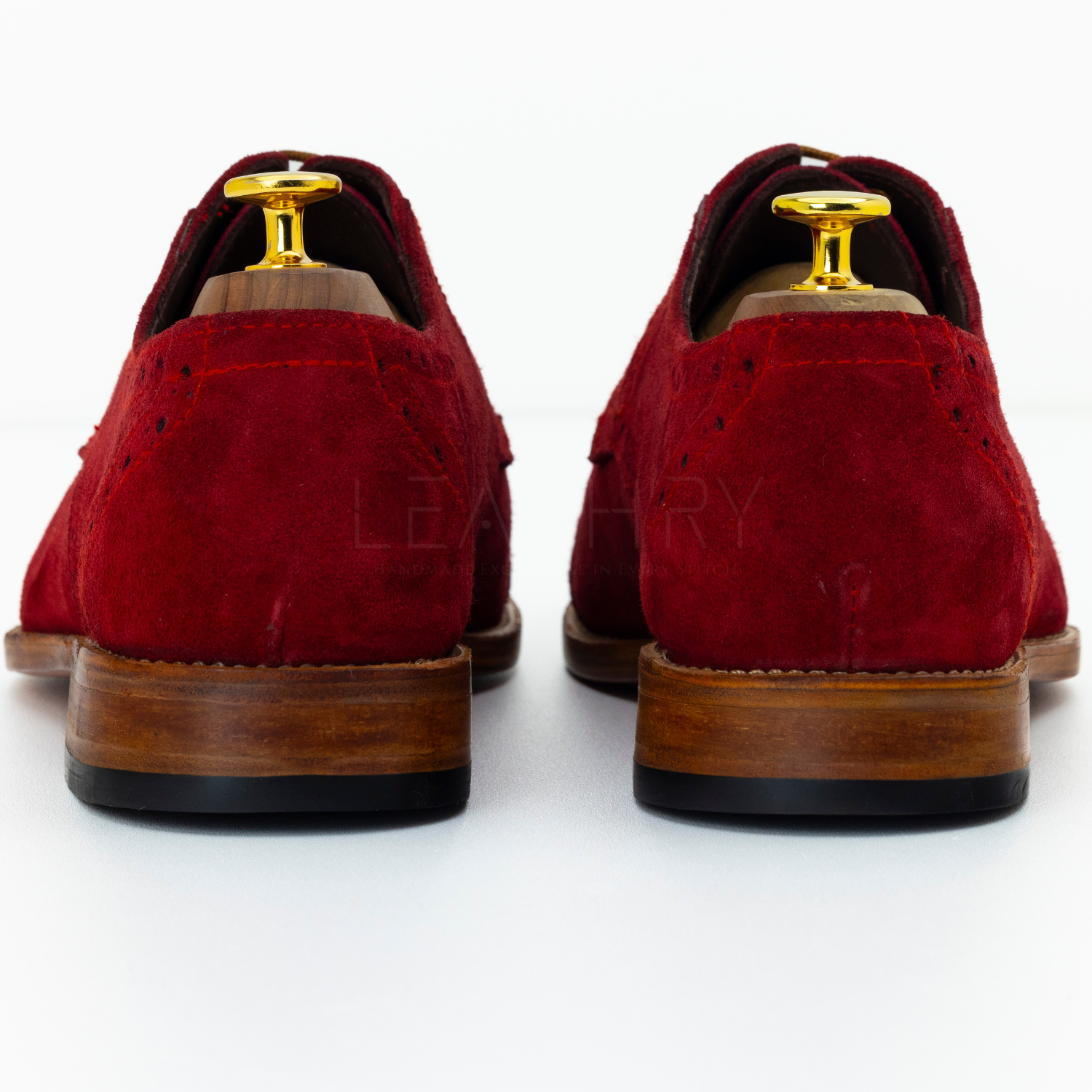 Red suede shoes with wooden soles on a white background