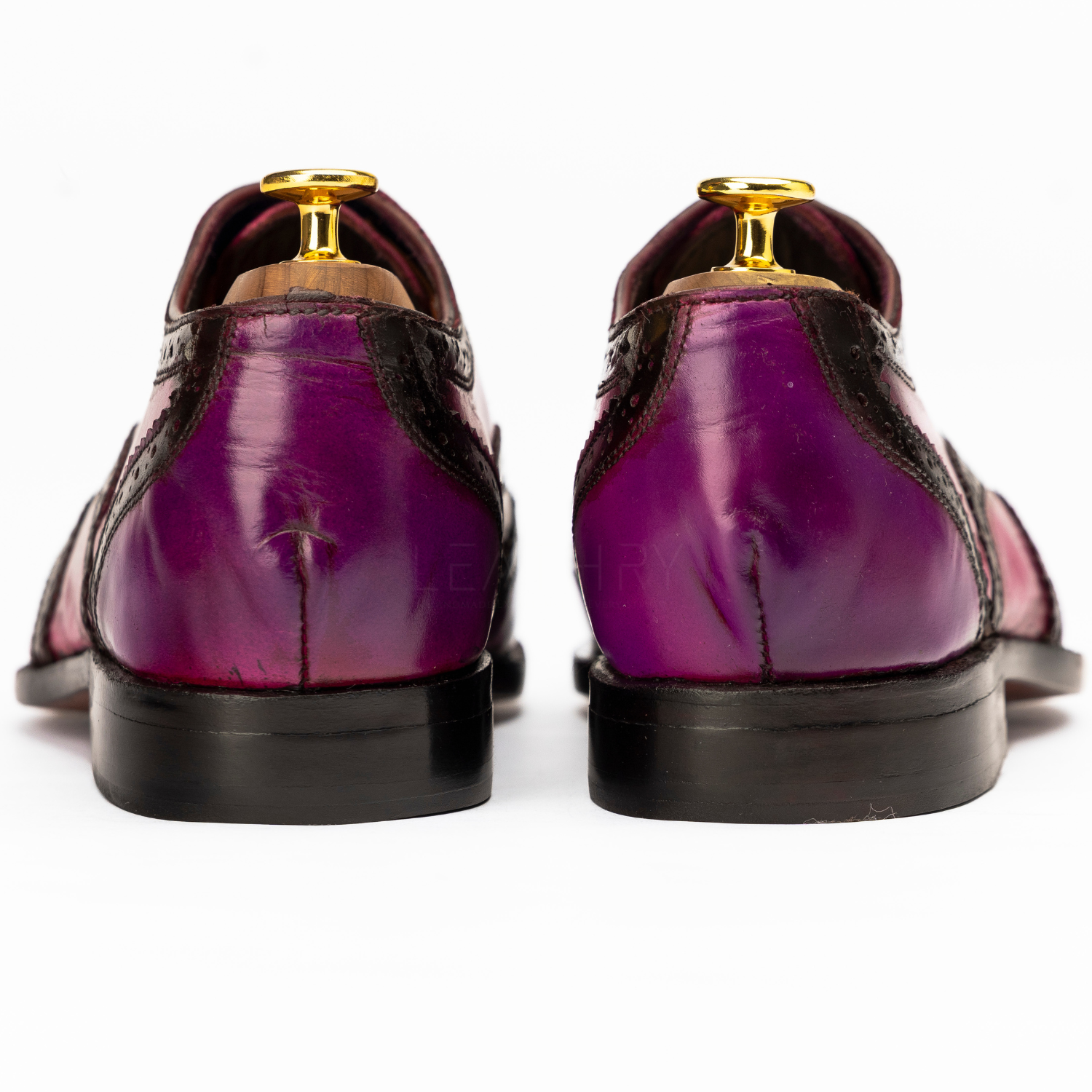 Purple dress shoes with gold accents on a white background
