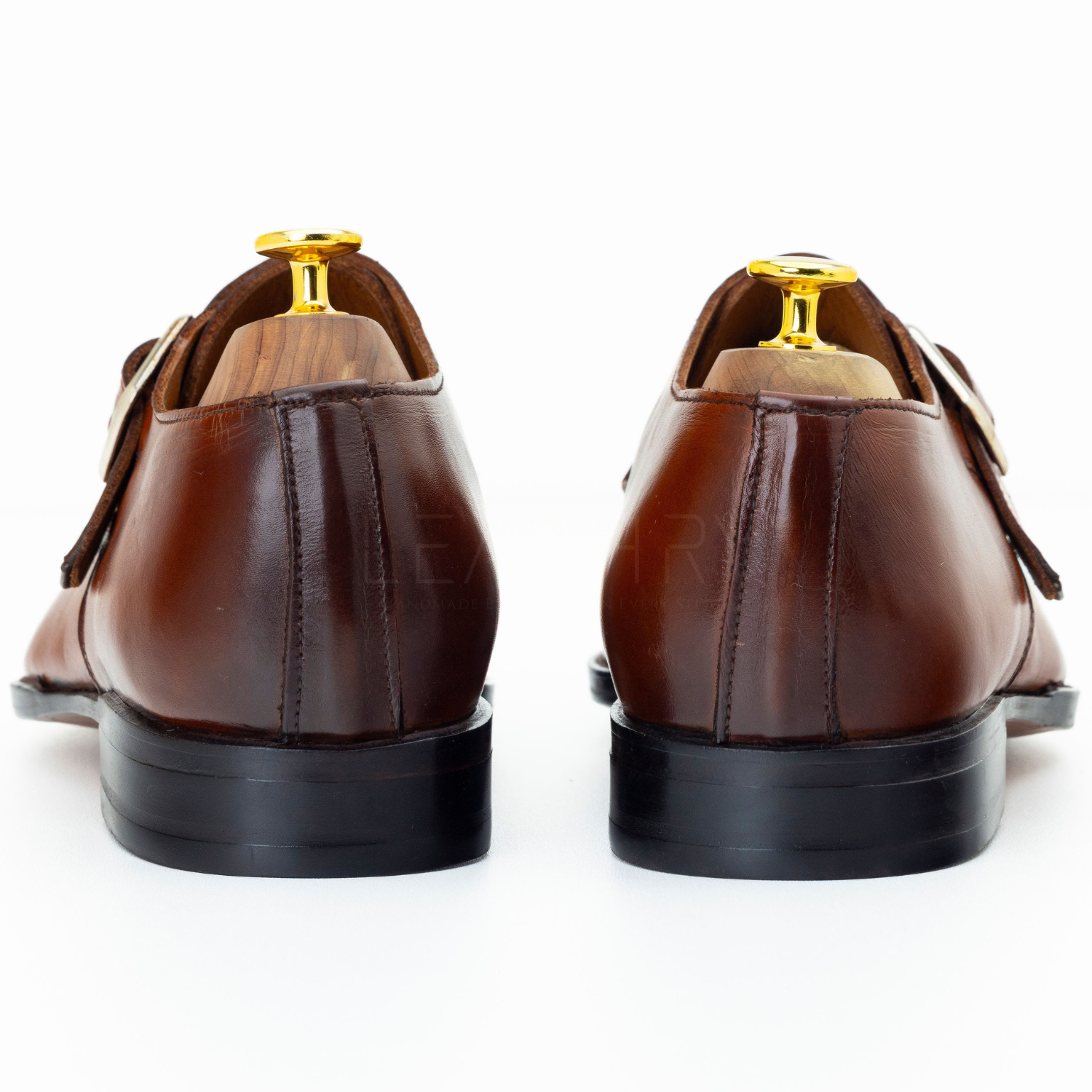 Brown leather shoes with gold buckles on a white background