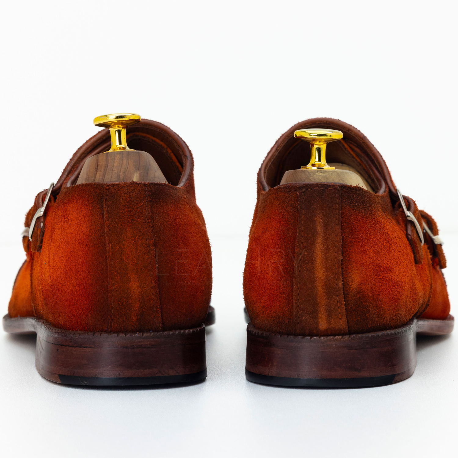 Pair of brown suede shoes with gold dress studs on a white background