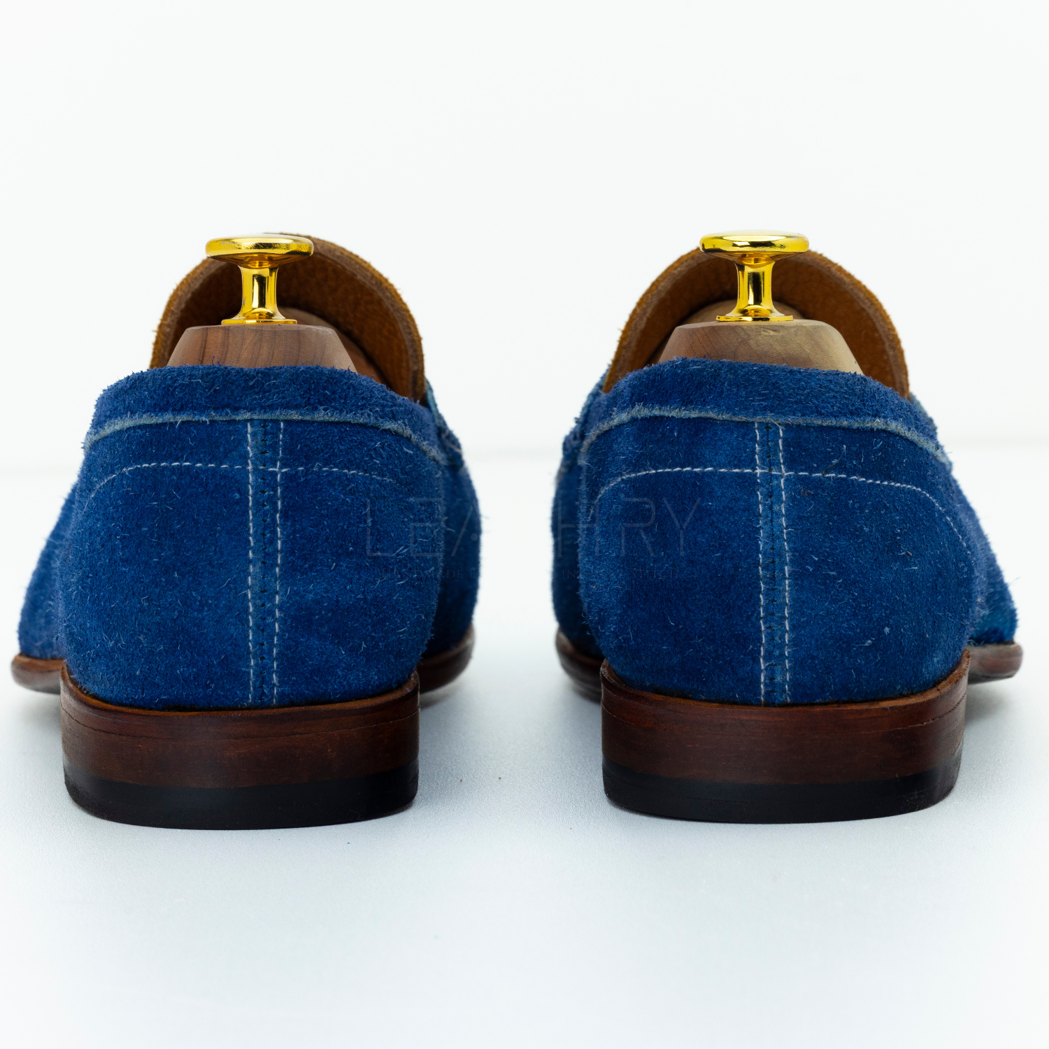Blue suede shoes with brown soles on a white background
