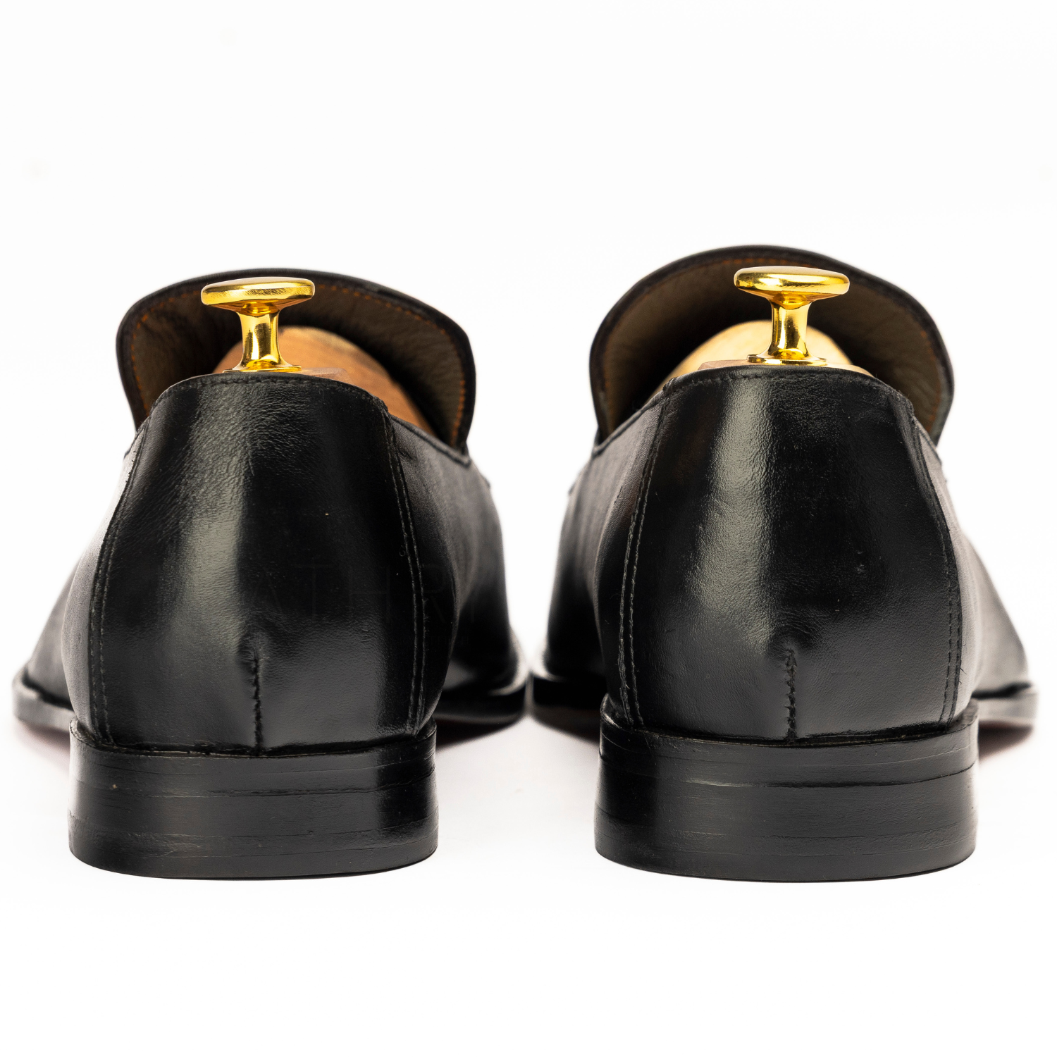 Black dress shoes with gold tips on a white background