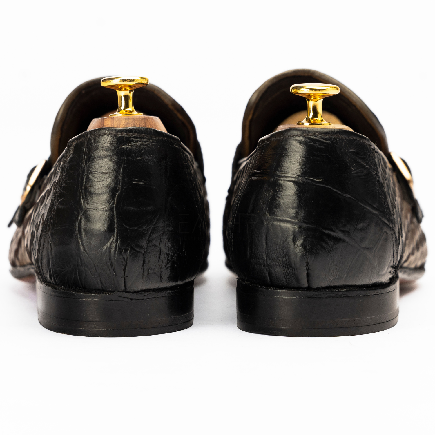 Black leather shoes with gold dress studs on a white background