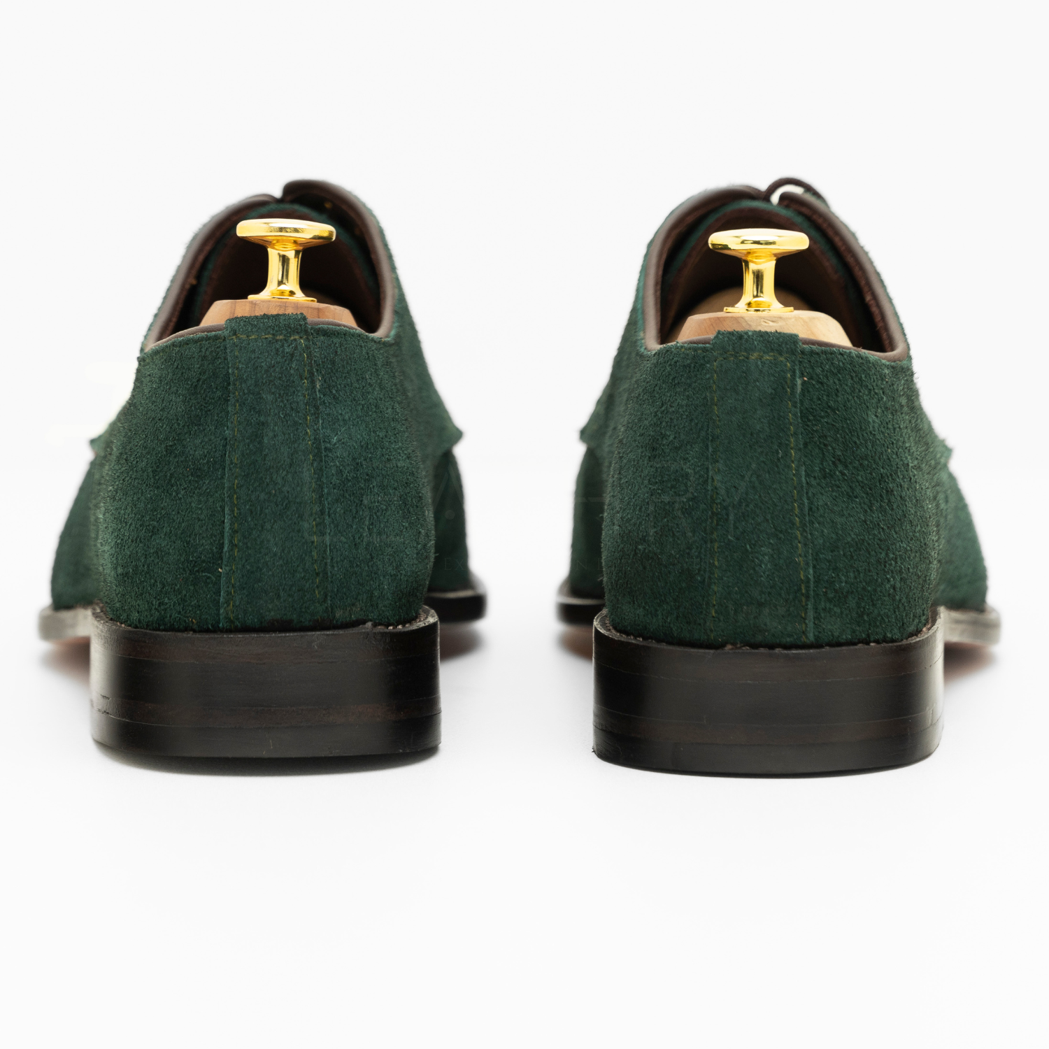 Green suede shoes with gold dress studs on a white background