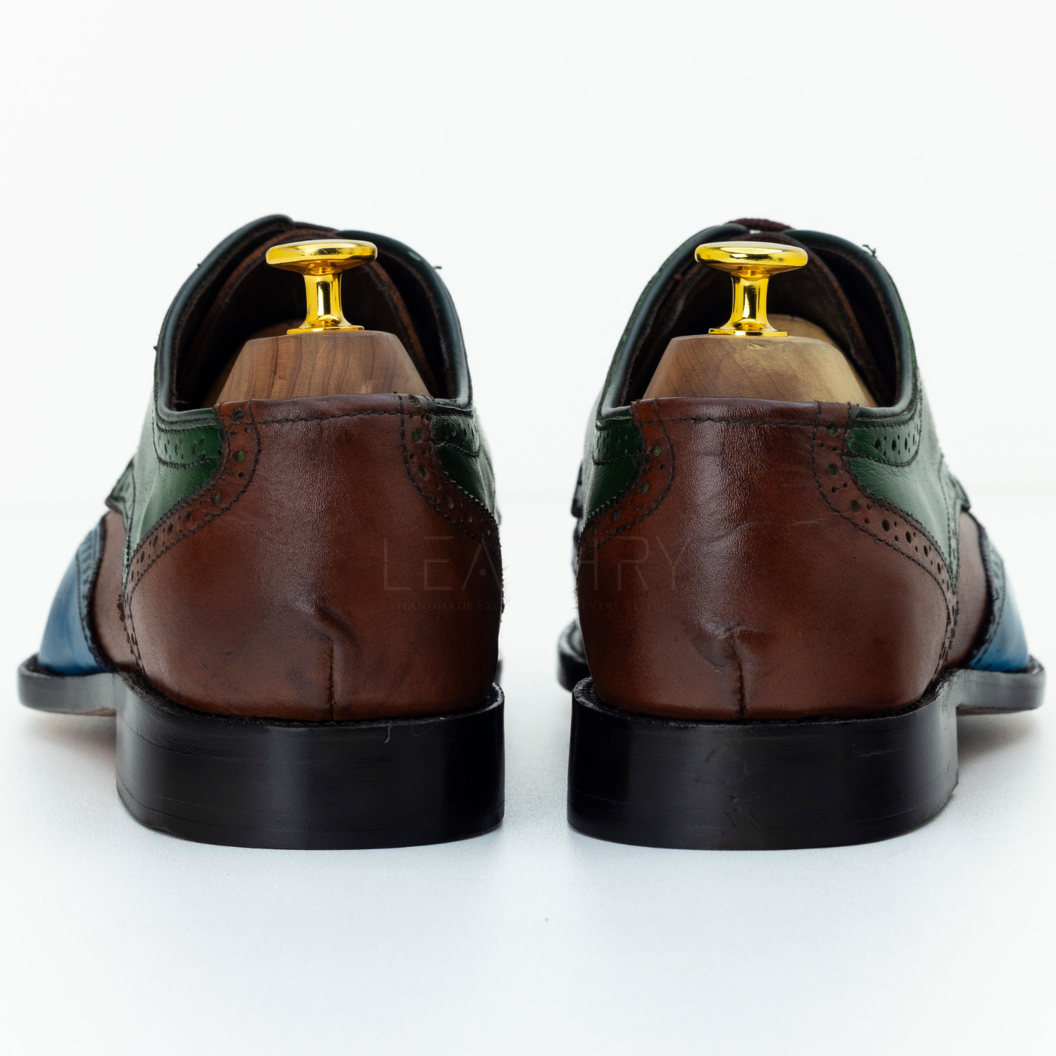 Brown leather shoes with green accents on a white background