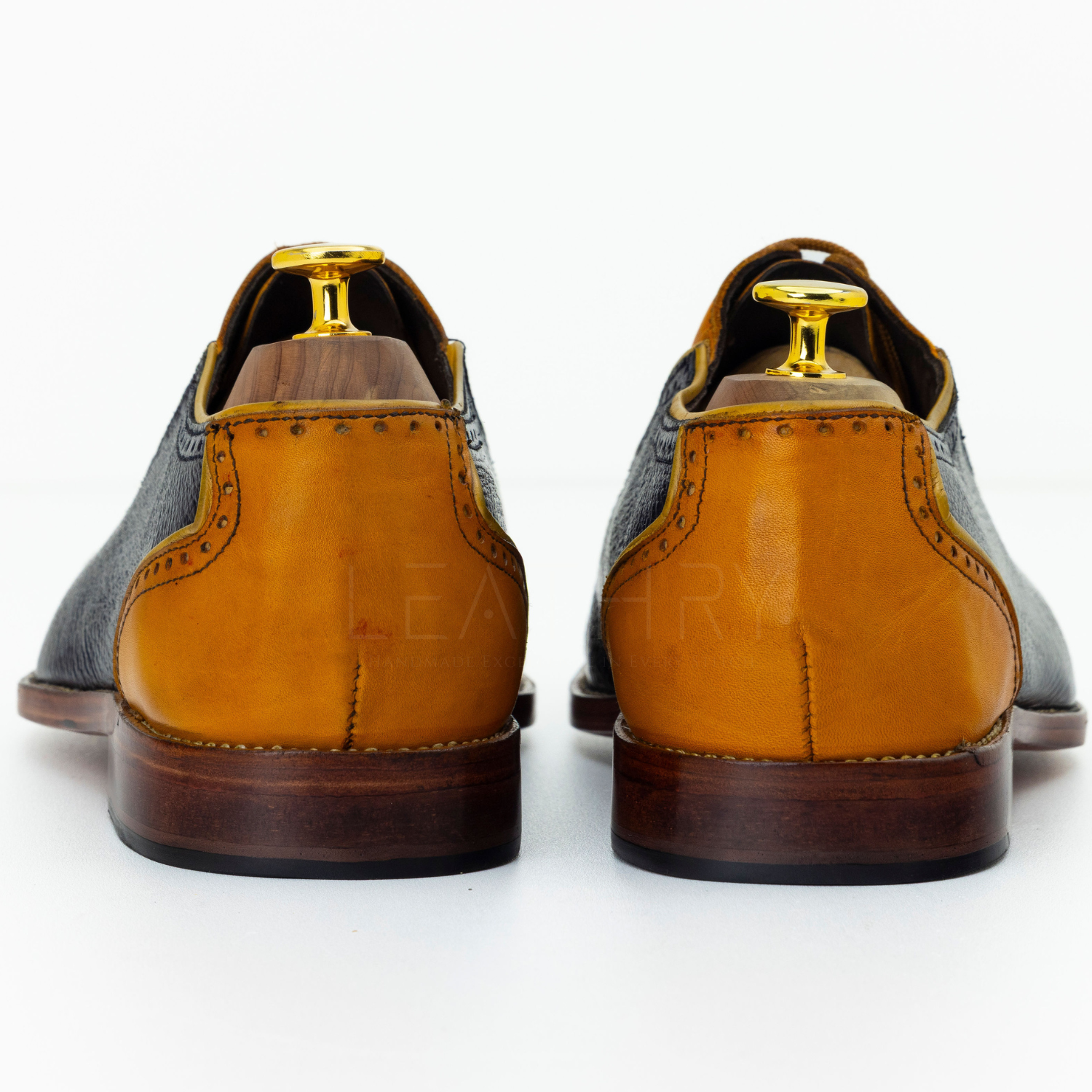 Pair of brown leather shoes with gold accents on a white background