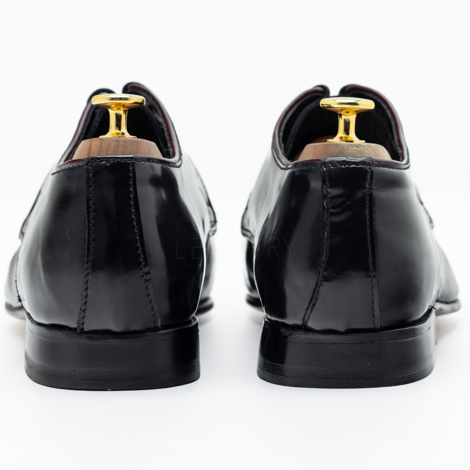 Black patent leather shoes with gold tips on a white background