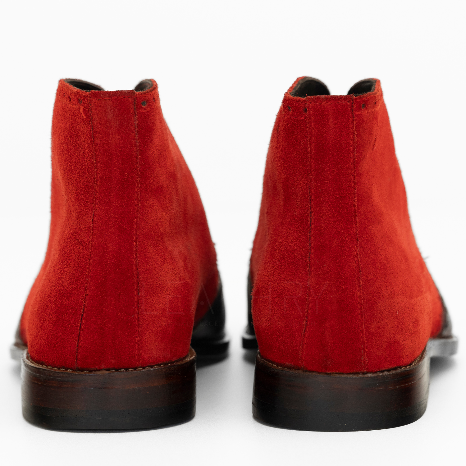 Pair of red suede ankle boots on a white background