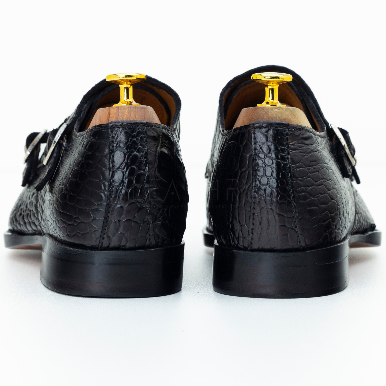 Black crocodile-patterned shoes with gold buckles on a white background