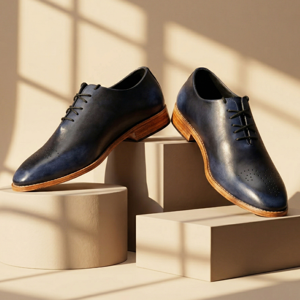 Pair of navy leather shoes with brown soles on a neutral background