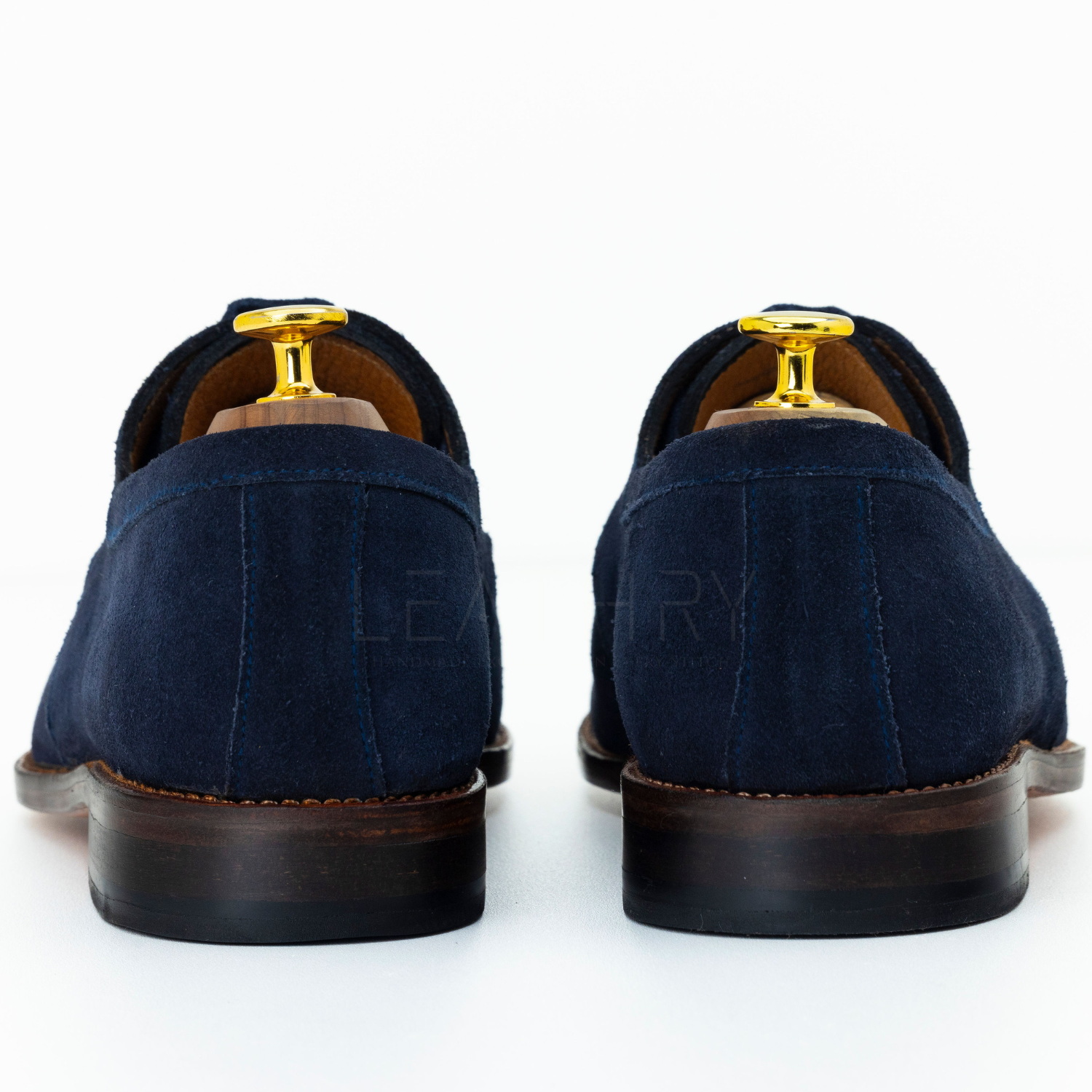 Navy blue suede shoes with gold accents on a white background