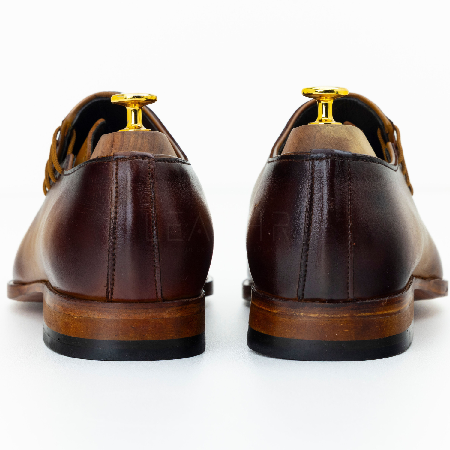 Brown dress shoes with gold accents on a white background