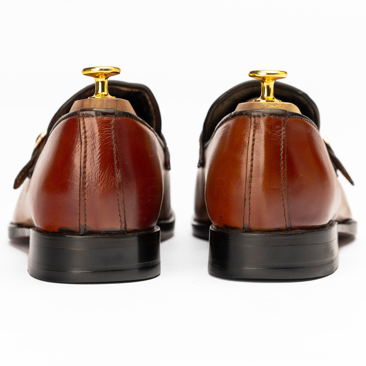 Brown leather dress shoes with gold tips on a white background