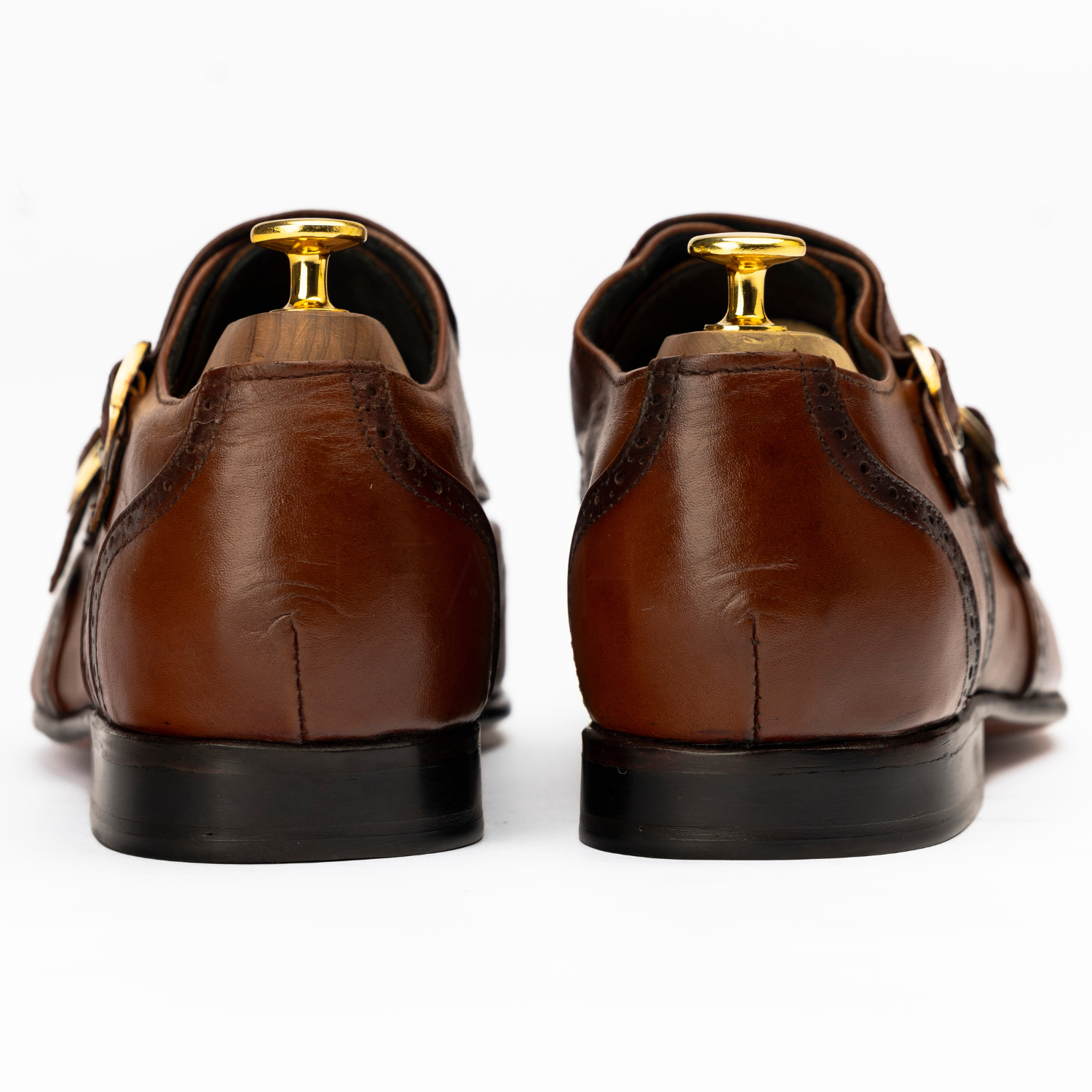 Brown leather shoes with gold accents on a white background