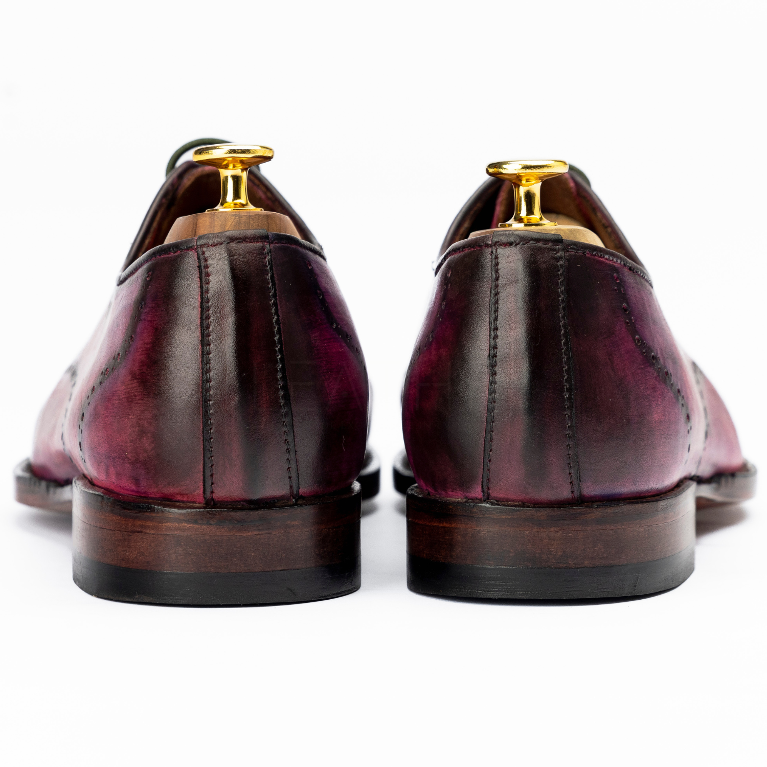Pair of brown leather shoes with gold accents on a white background