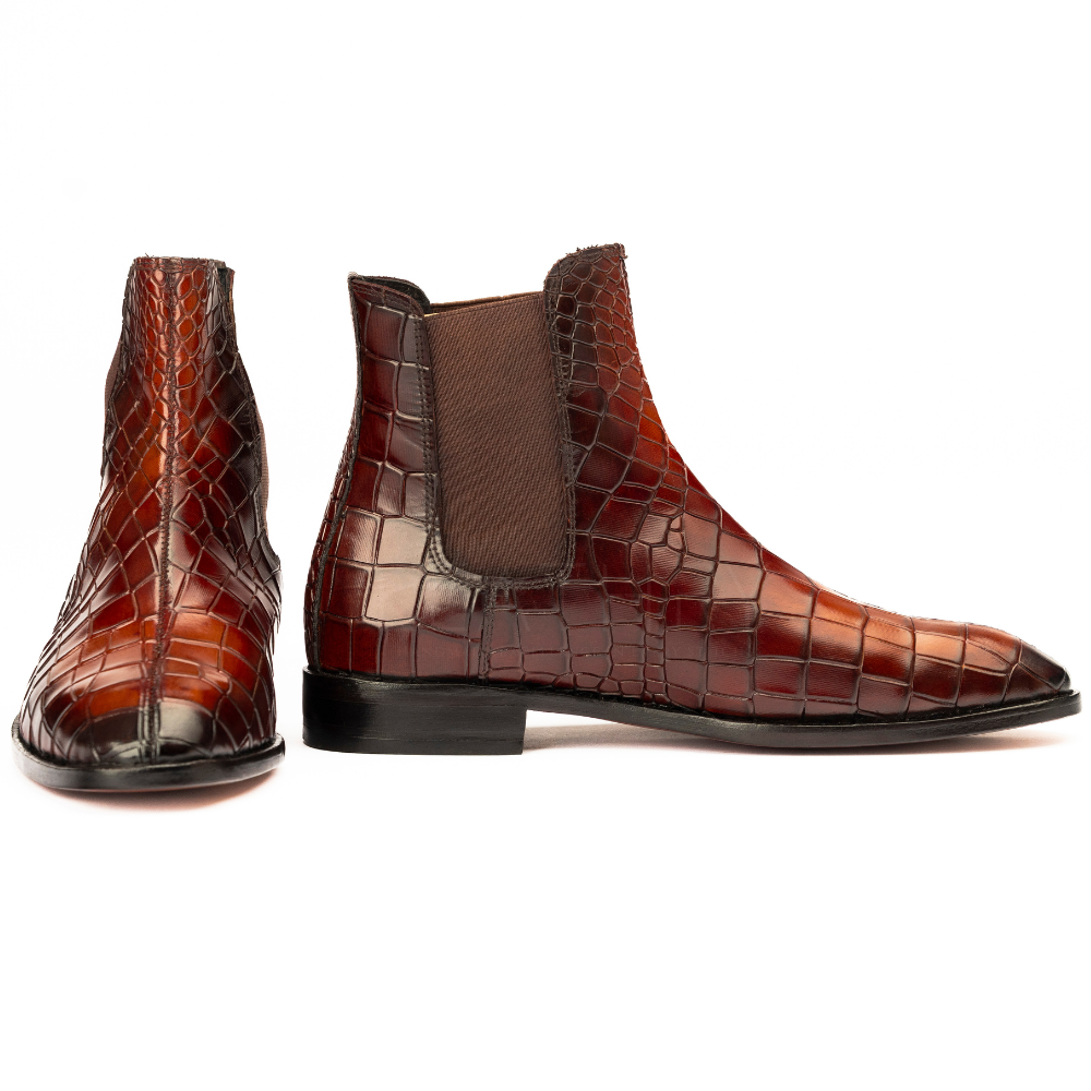 Brown crocodile-patterned leather boots on a white background