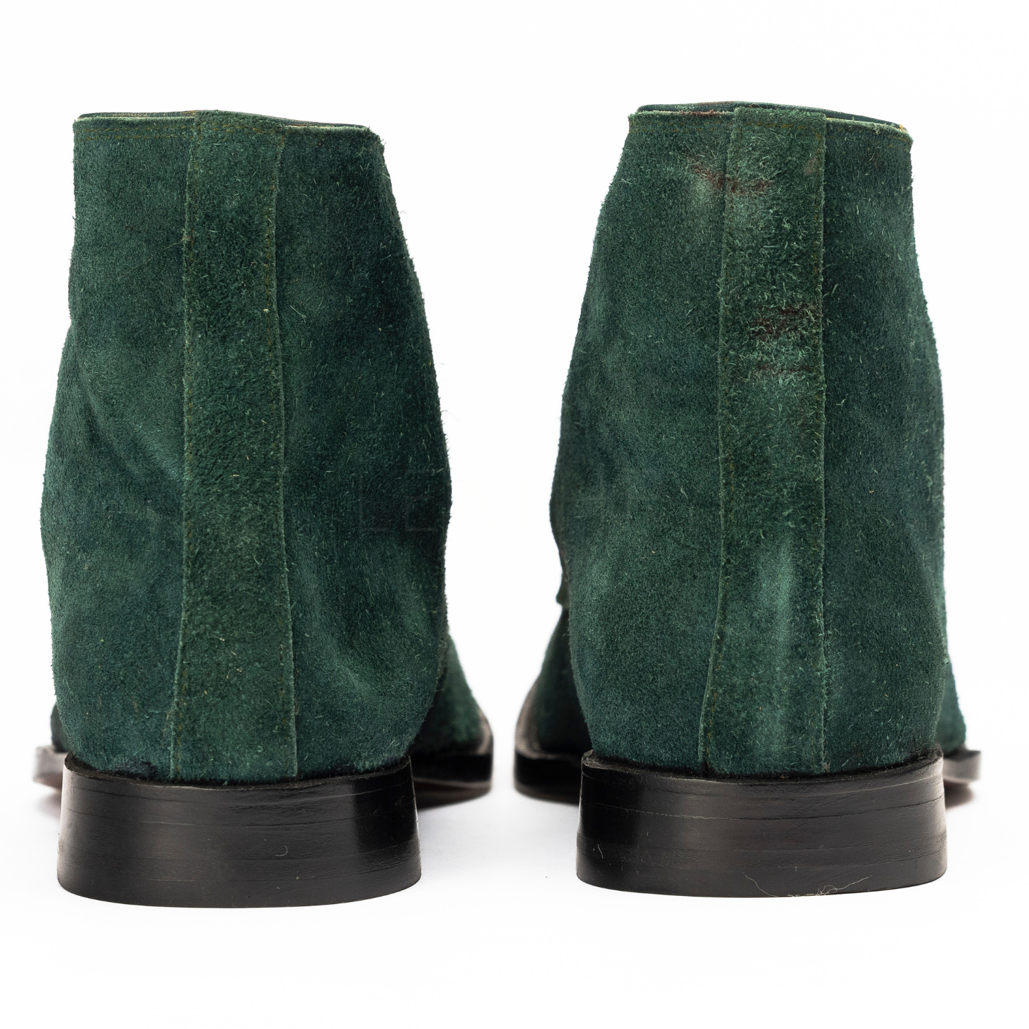 Green suede boots with black soles on a white background