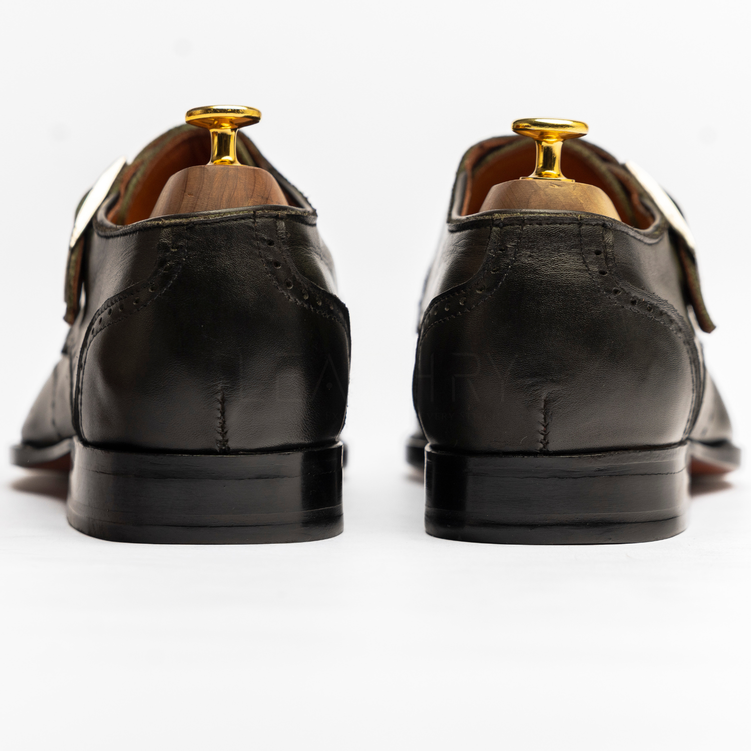 Black leather shoes with gold buckles on a white background