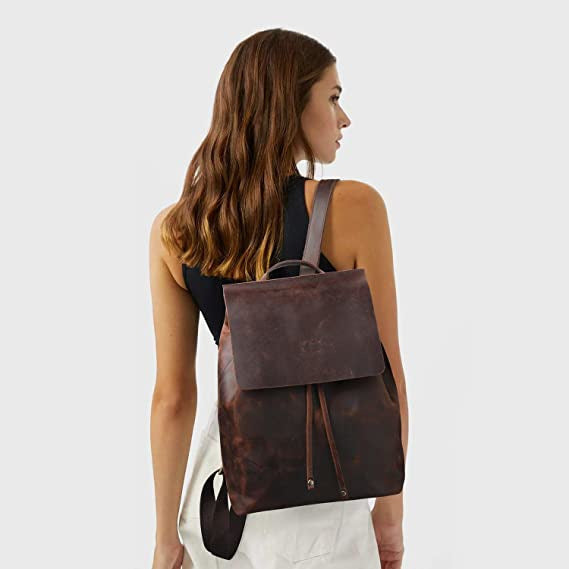 Woman wearing a brown leather backpack on a plain background