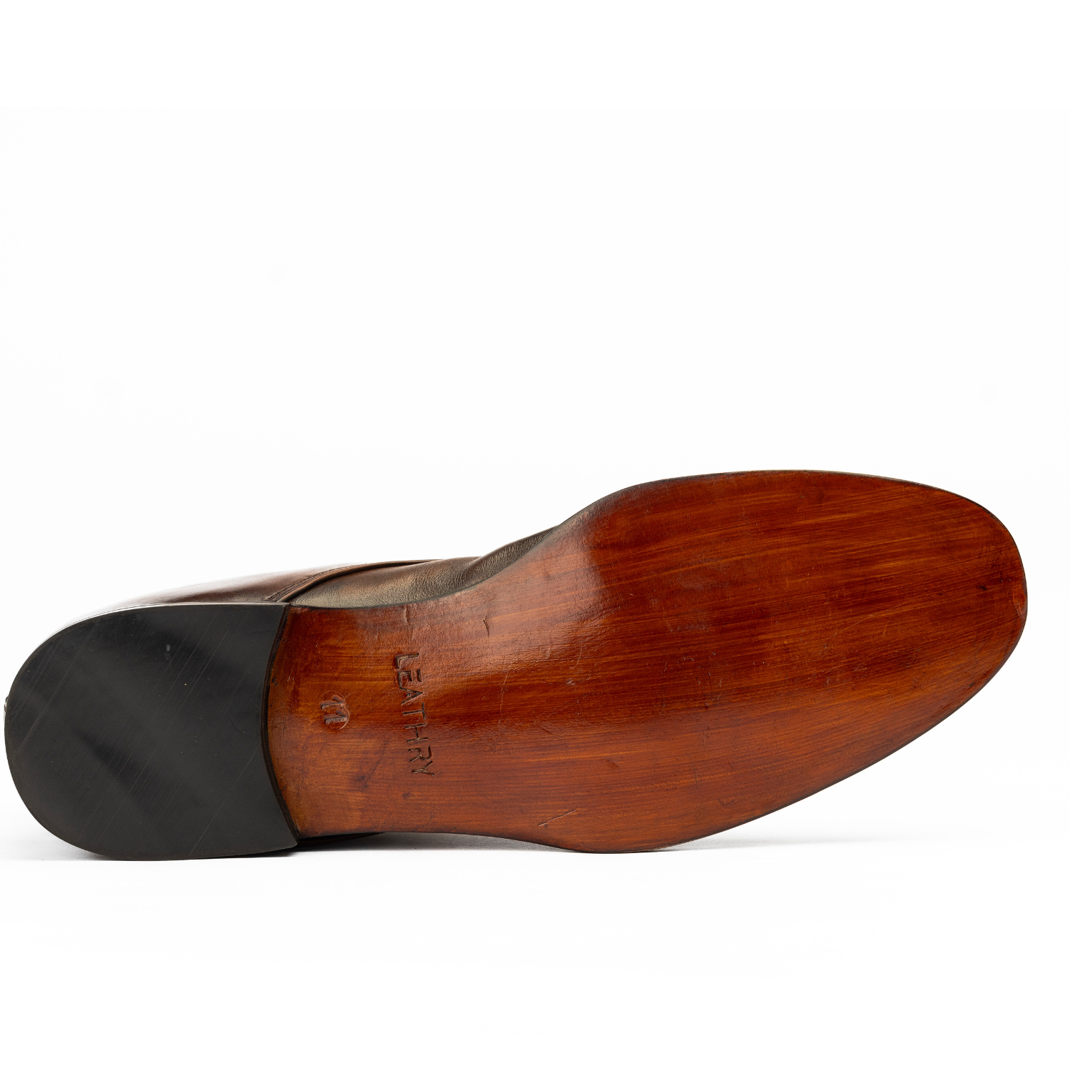 Close-up of a wooden shoe sole with a black heel on a white background