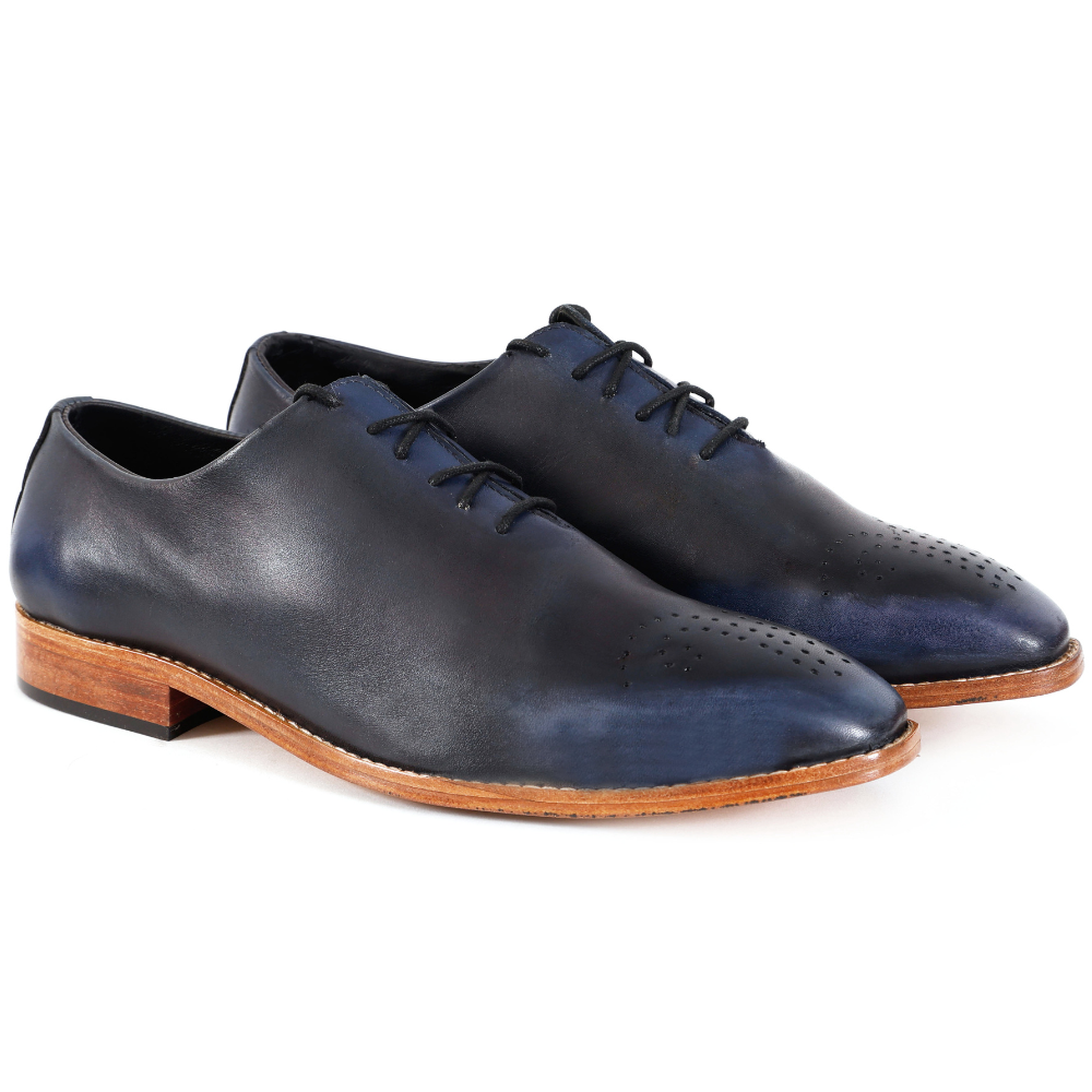 Pair of navy leather dress shoes with brown soles on a white background