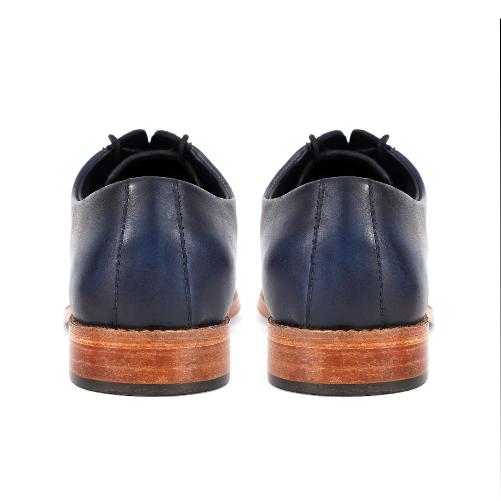 Pair of navy blue leather shoes with brown soles on a white background