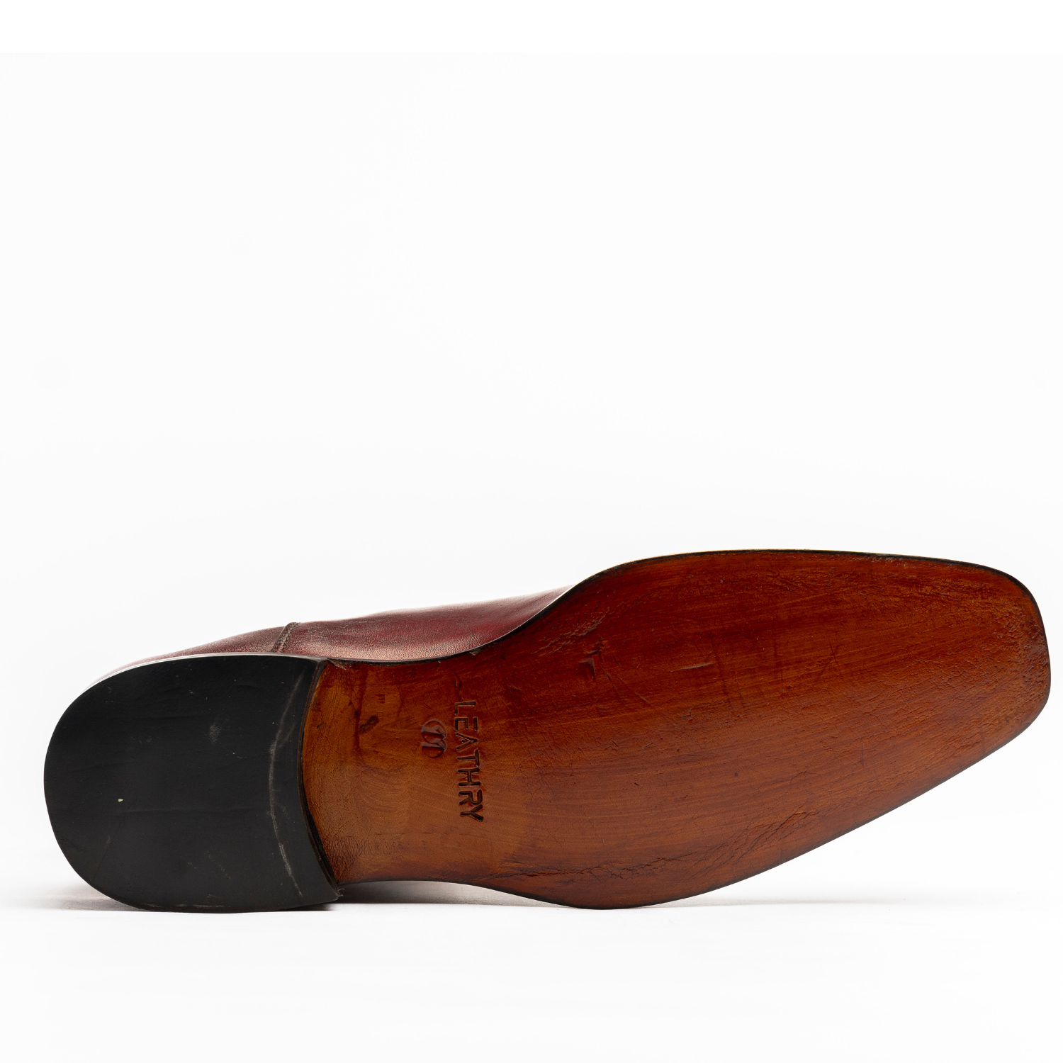 Brown leather shoe sole with black rubber outsole on a white background